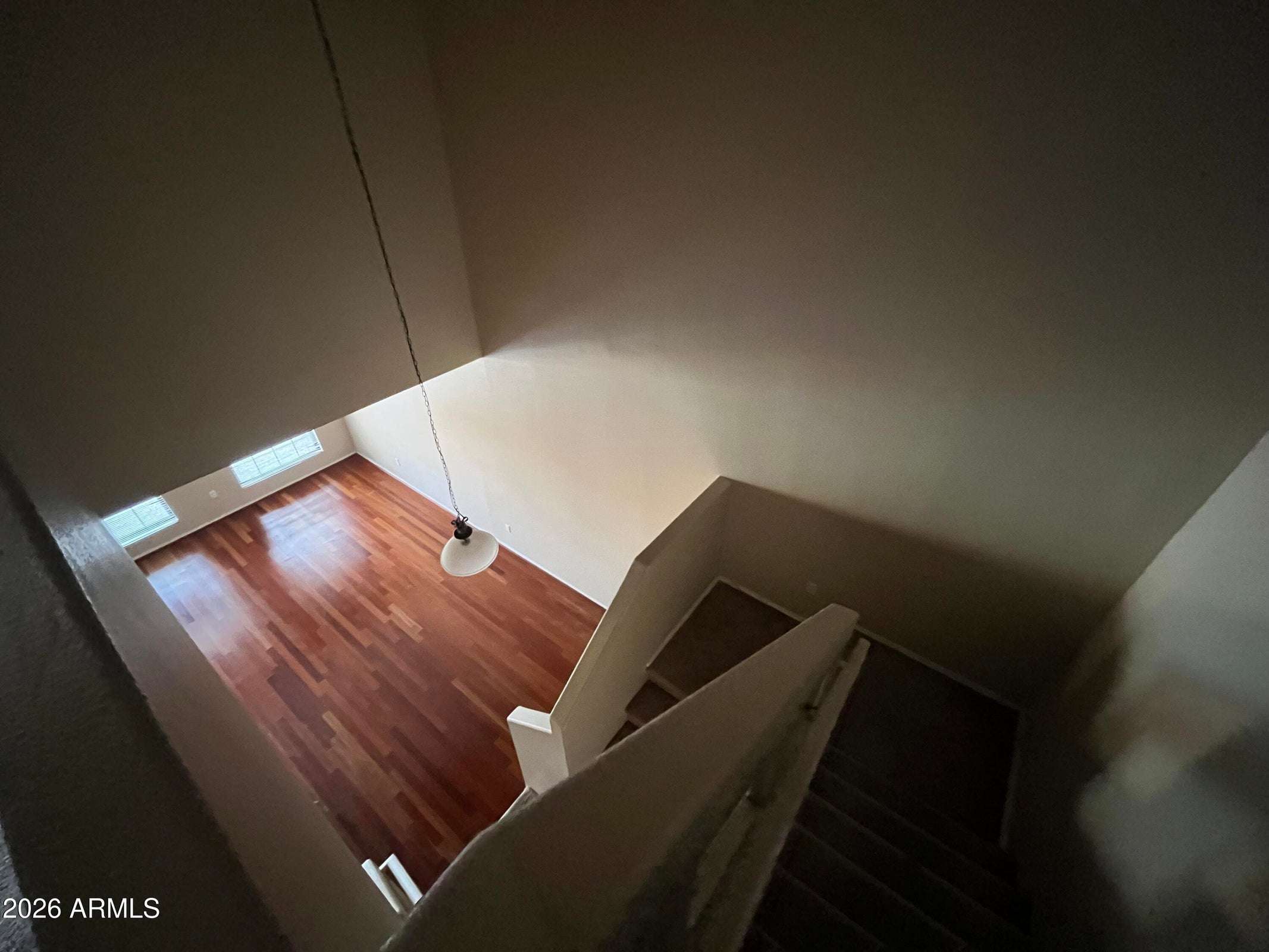 16 of 26. Looking down from the upper level, this photo captures the home's impressive vaulted ceilings, open staircase, and beautiful wood flooring that define the spacious living area.