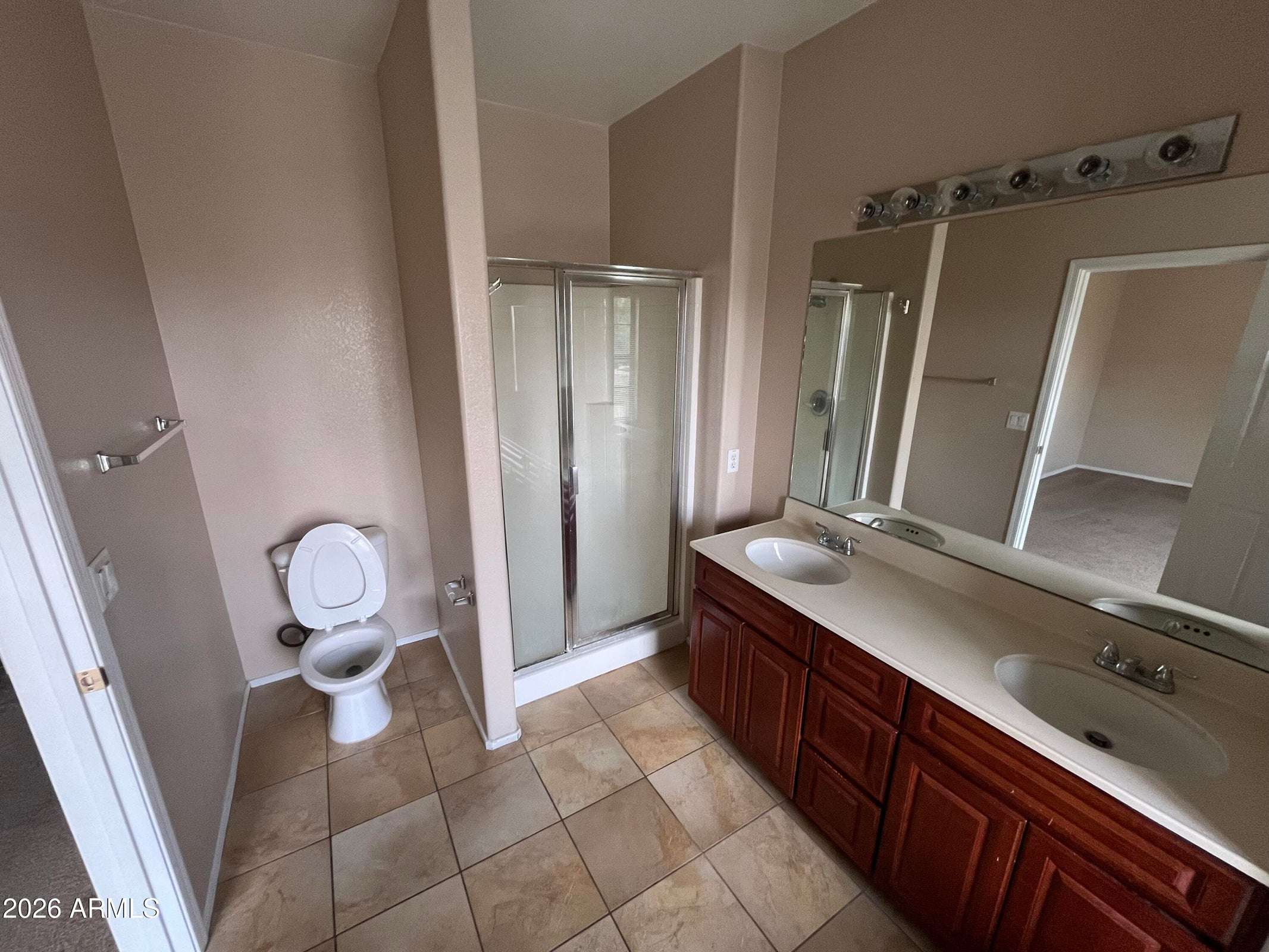 18 of 26. The primary bathroom features a large dual-sink vanity, expansive mirror, walk-in shower, and durable tile flooring, providing both comfort and functionality.