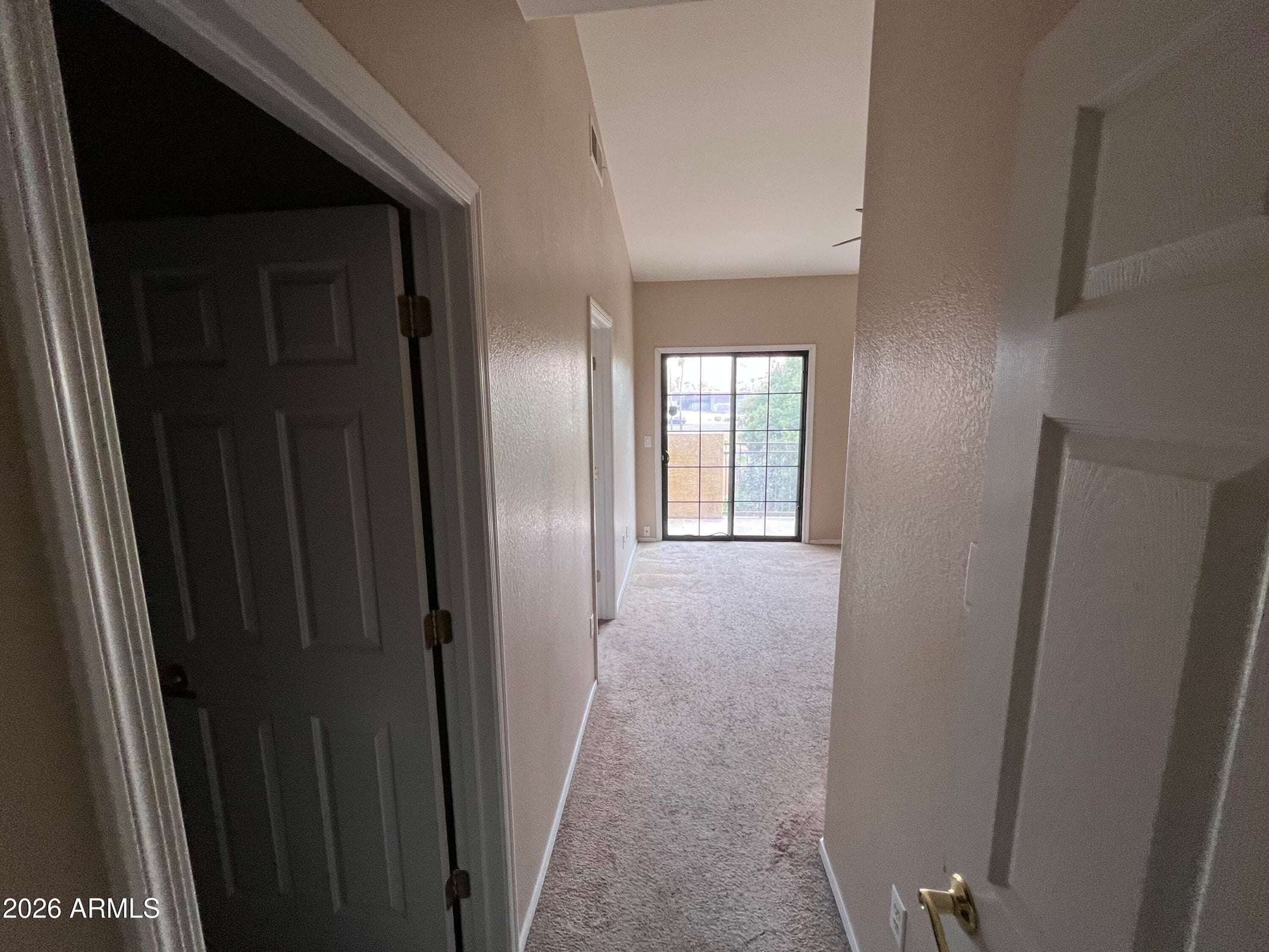 20 of 26. The hallway leads into the spacious primary suite, showcasing the home's functional layout, vaulted ceilings, and easy access to the private balcony and ensuite bathroom.