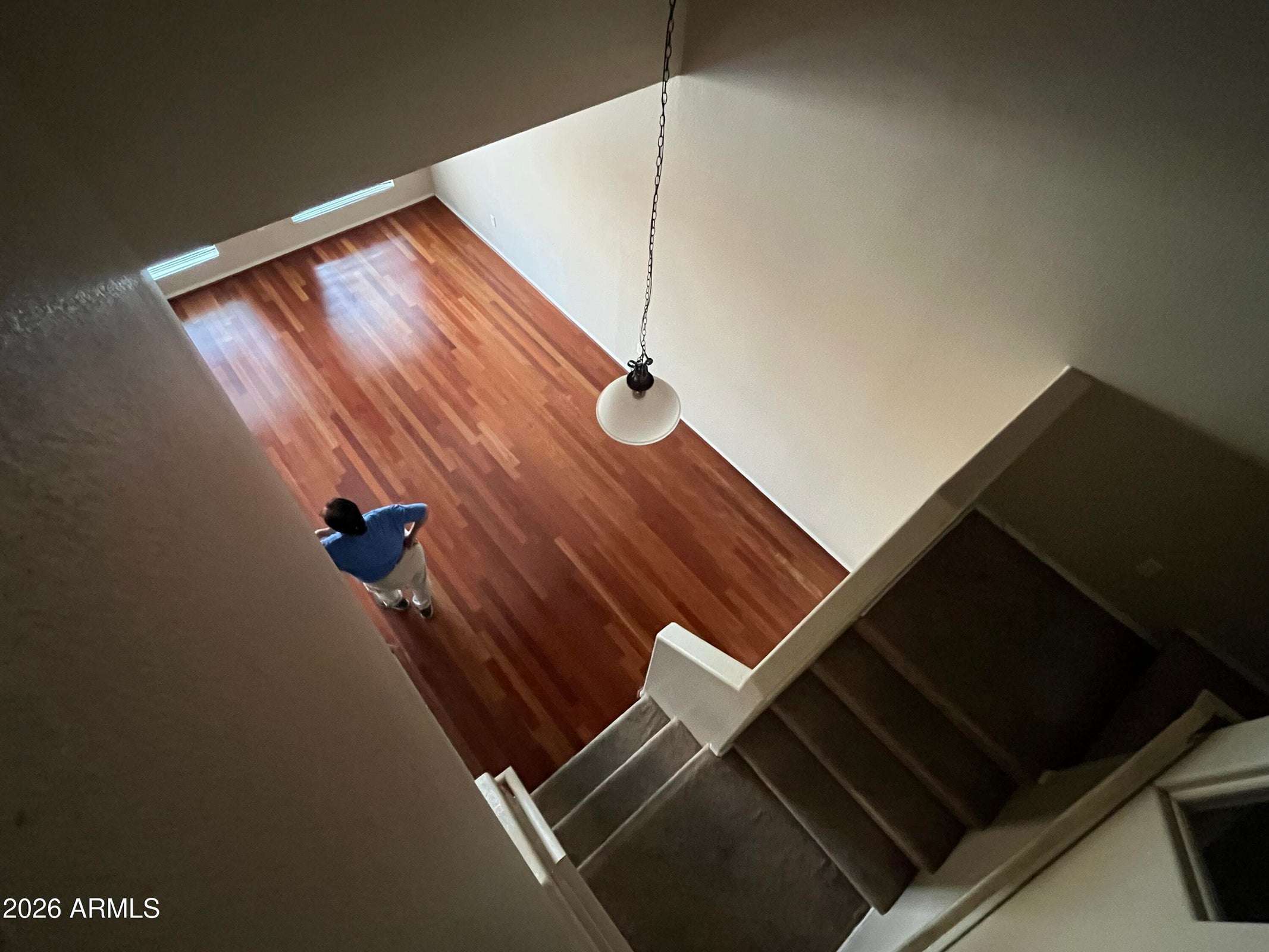 21 of 26. An elevated perspective highlights the dramatic two-story great room with beautiful wood flooring, soaring ceilings, and an open staircase that enhances the spacious feel of this Phoenix home.