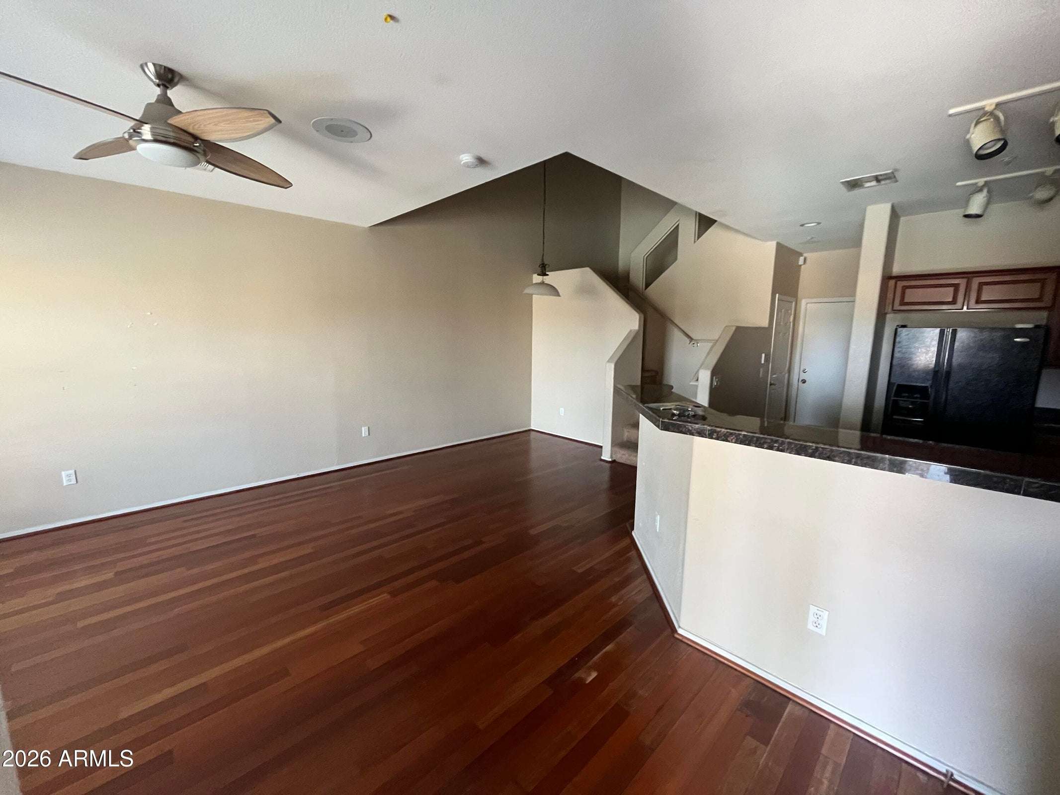 22 of 26. The open living room offers soaring ceilings, attractive wood flooring, ceiling fan, and seamless access to the kitchen, creating a welcoming space designed for comfortable everyday living.