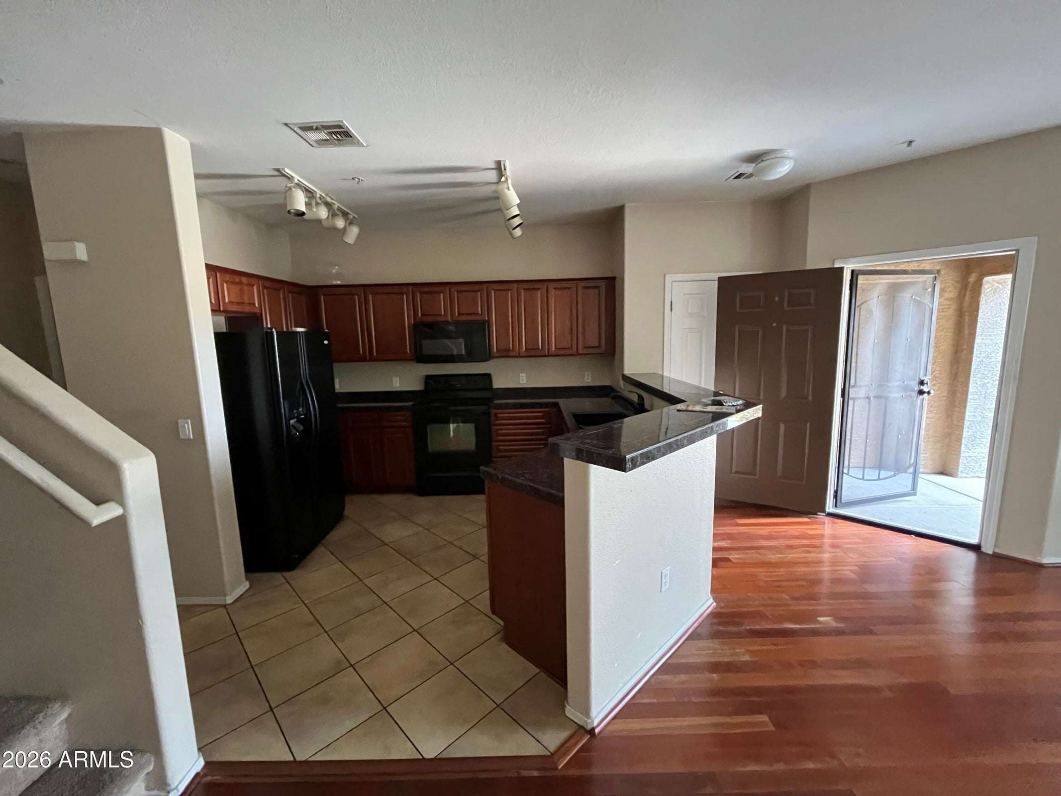 23 of 26. Designed for convenience, the kitchen features generous cabinetry, black appliances, durable tile flooring, and a breakfast bar that connects effortlessly to the open-concept living area.