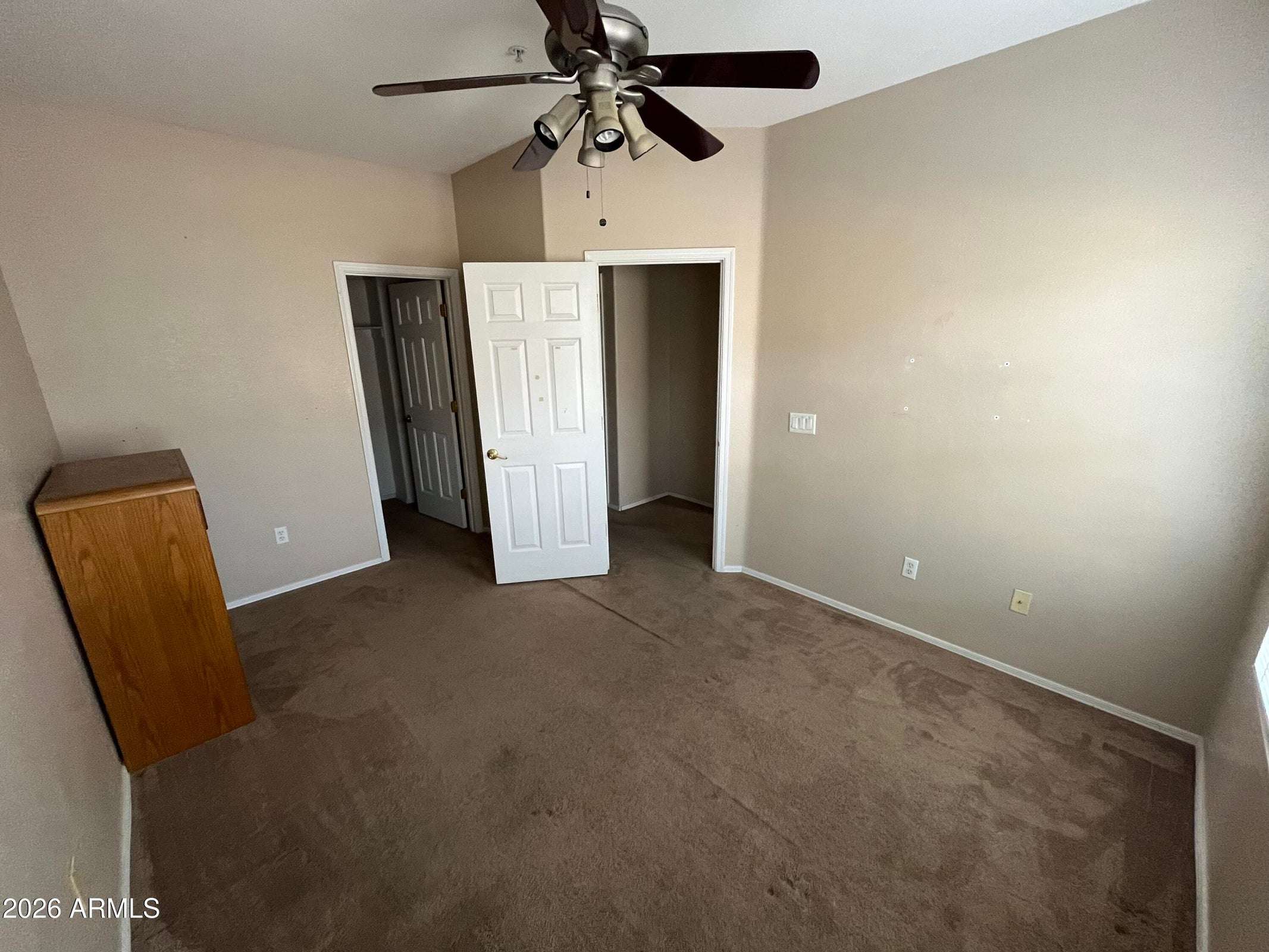 24 of 26. A spacious secondary bedroom with vaulted ceilings, plush carpeting, ceiling fan, and a large closet offers flexible living options for guests, family members, or a home office.