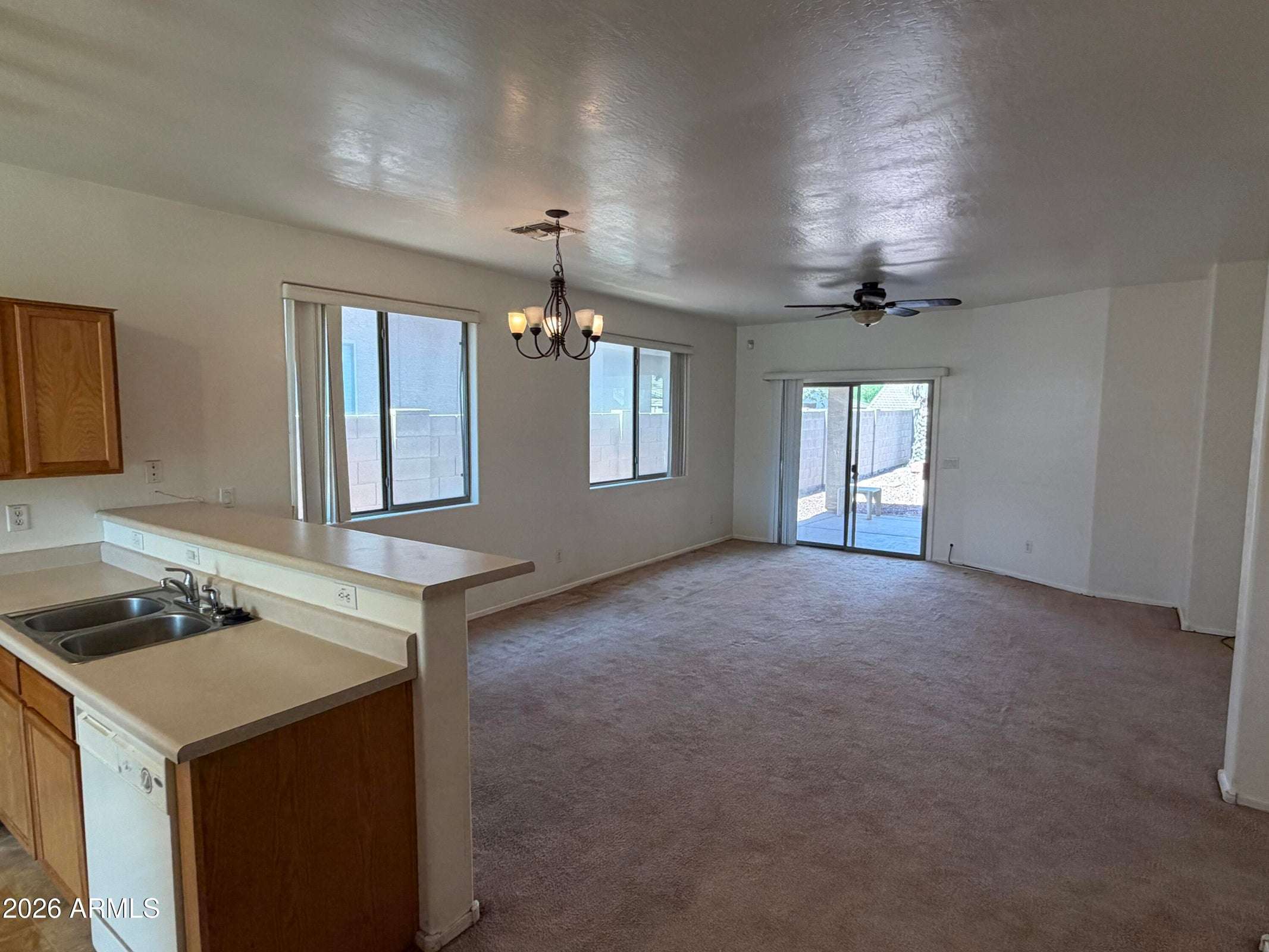 4 of 31. Expansive living room with abundant natural light, ceiling fan, and direct access to the backyard patio. The open floor plan creates a comfortable space for everyday living and entertaining.