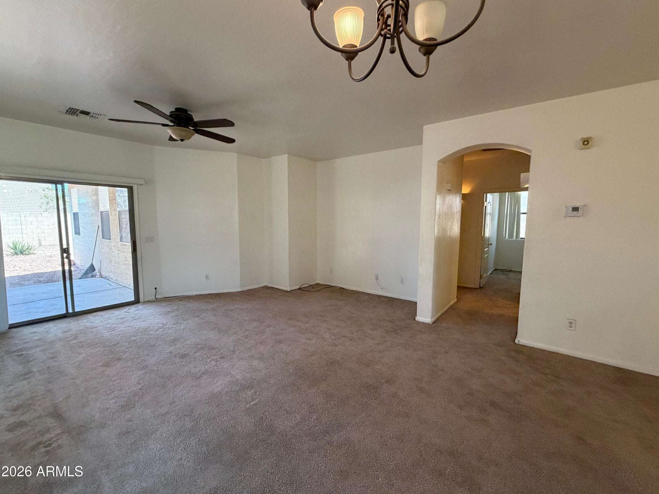 11 of 31. Spacious living area with ceiling fan, plush carpeting, and sliding door access to the backyard patio. The open layout provides excellent flexibility for everyday living and entertaining.