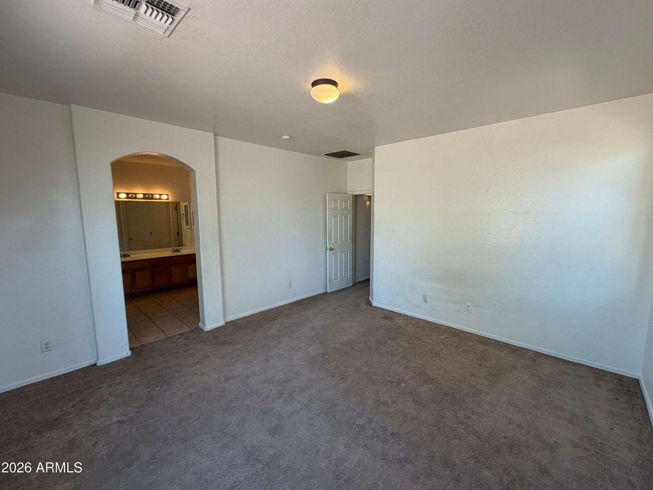 16 of 31. Spacious primary suite with plush carpeting, natural light, and private access to the ensuite bath and walk-in closet. A comfortable retreat after a long day.