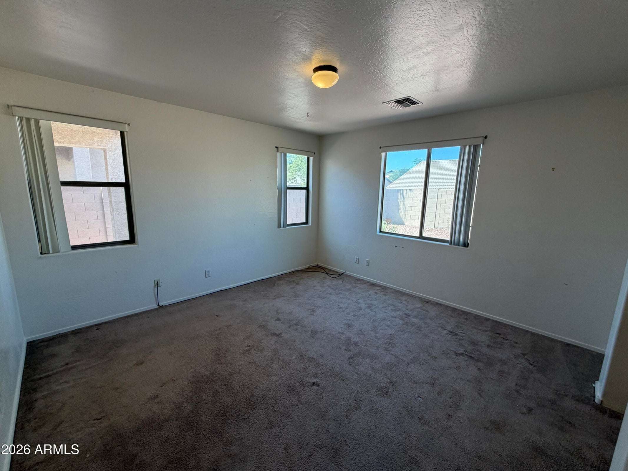 17 of 31. Bright secondary bedroom with large windows, comfortable carpeting, and flexible space suitable for guests, family, or a home office setup.