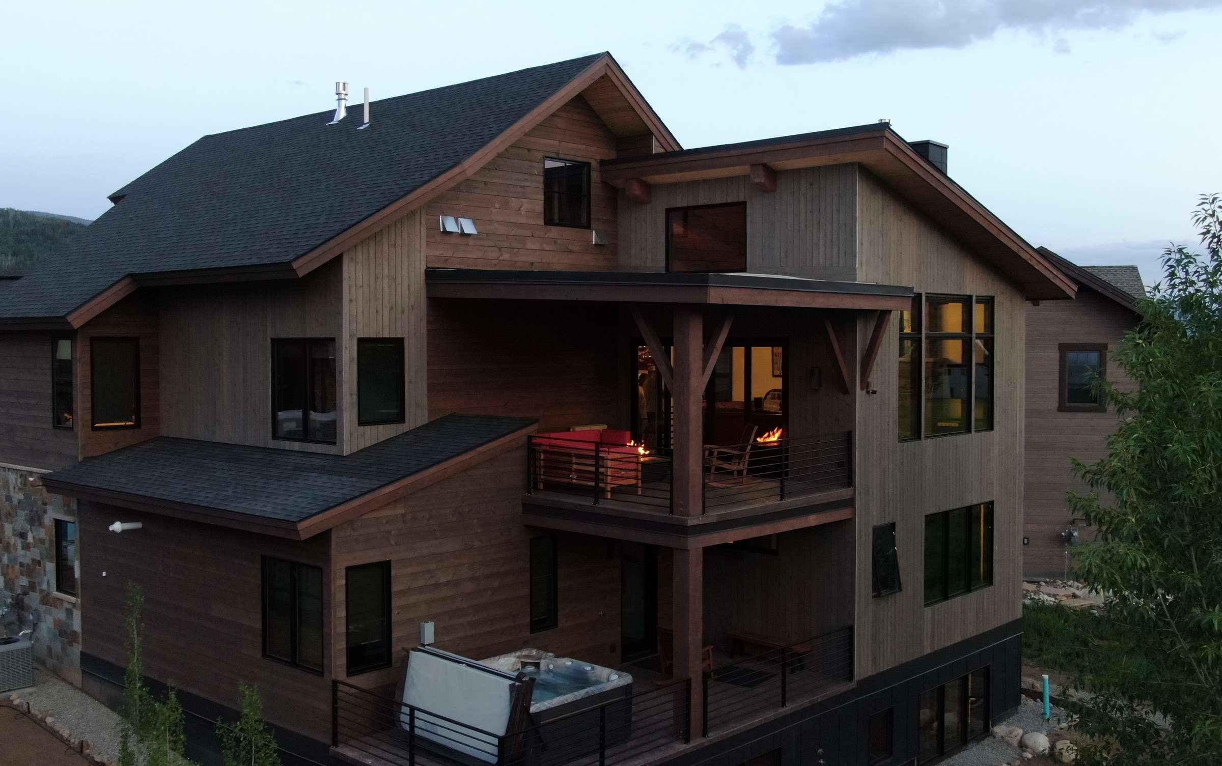 34 of 42. Modern mountain home featuring expansive outdoor spaces, a hot tub, and stunning views, perfect for relaxation. Back exterior.