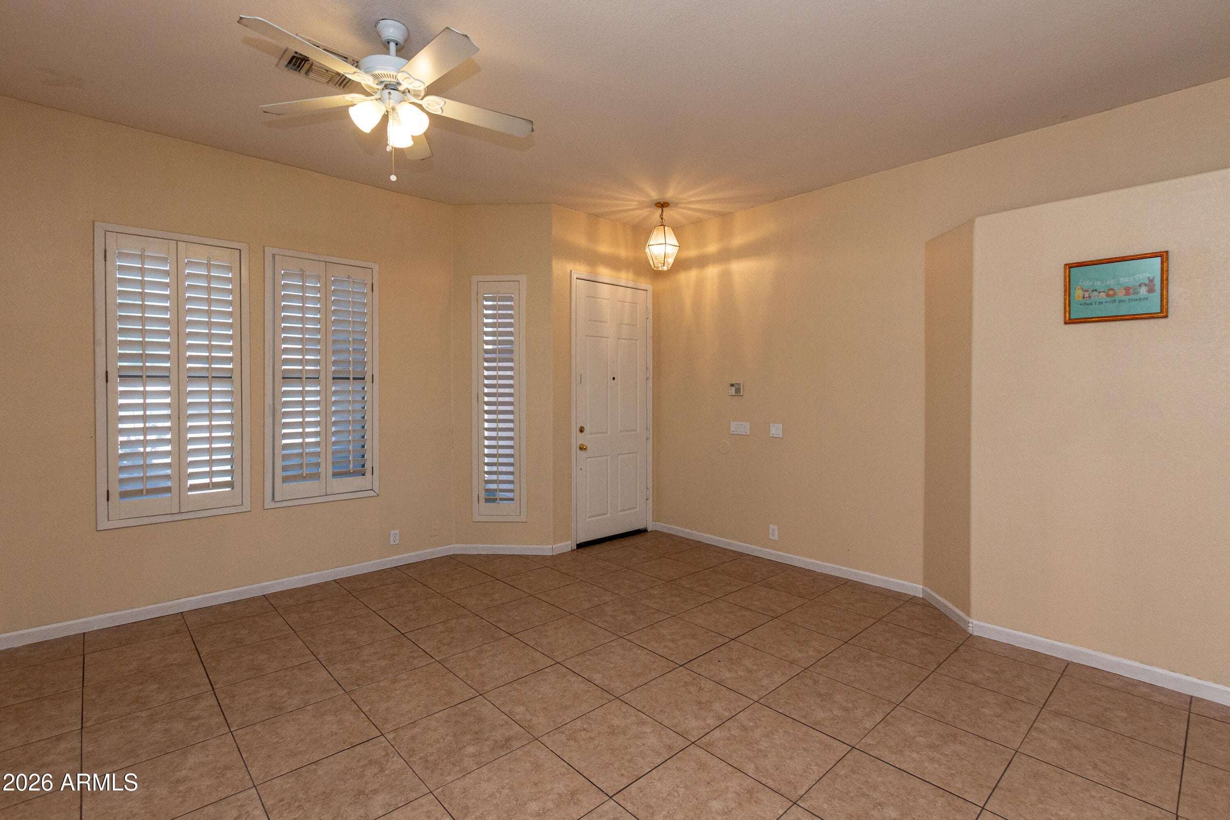 5 of 29. Comfortable living area with large windows, plantation shutters, and durable tile flooring. A welcoming space that blends functionality and elegance near the home's main entry.