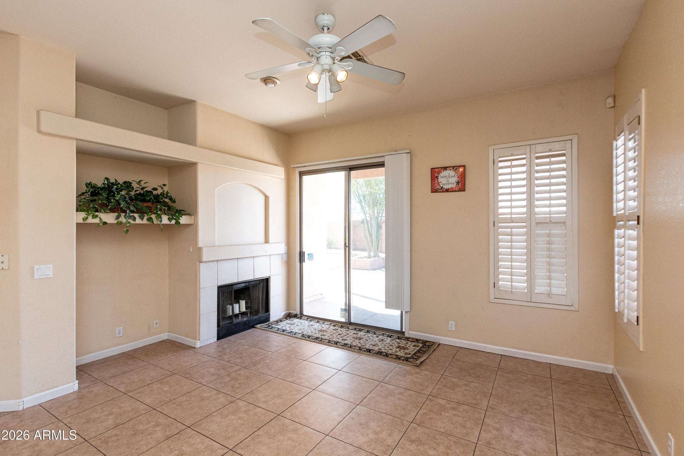 7 of 29. Relaxing family room featuring a fireplace, ceiling fan, and sliding glass door access to the backyard. A comfortable gathering space perfect for year-round enjoyment.