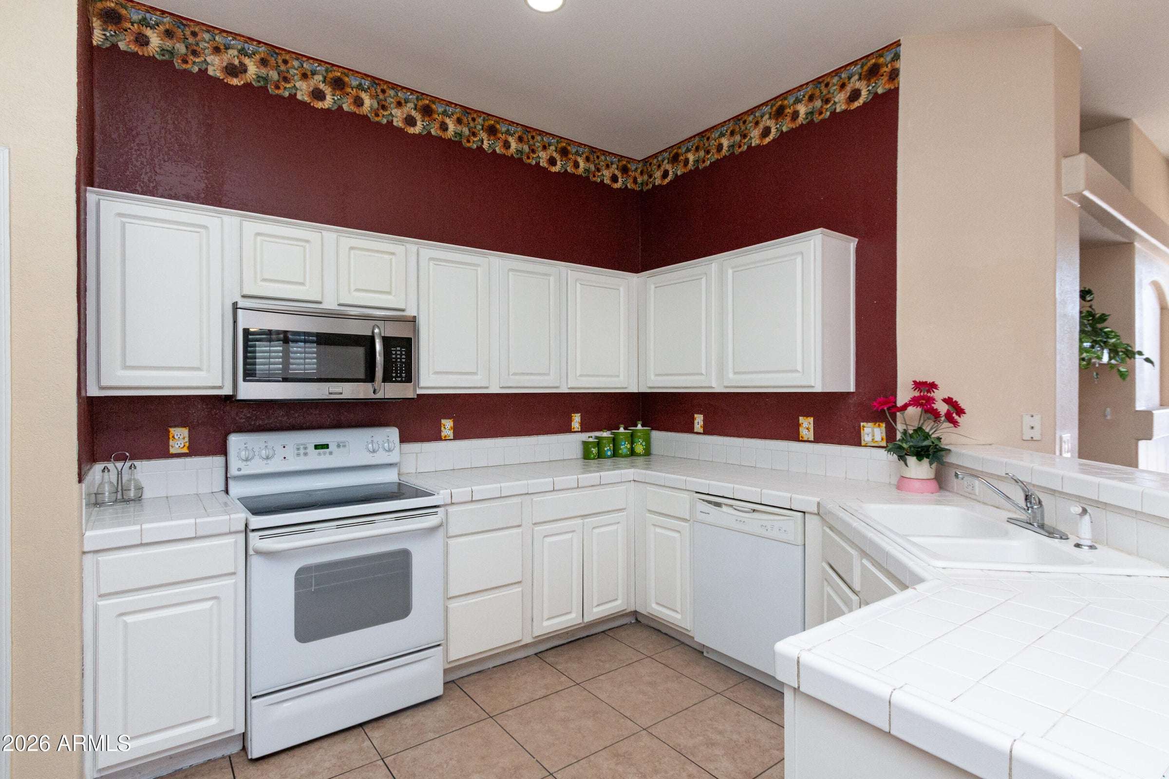 12 of 29. Well-appointed kitchen featuring plentiful cabinetry, tile countertops, and efficient workspace. The practical layout supports both everyday cooking and entertaining.