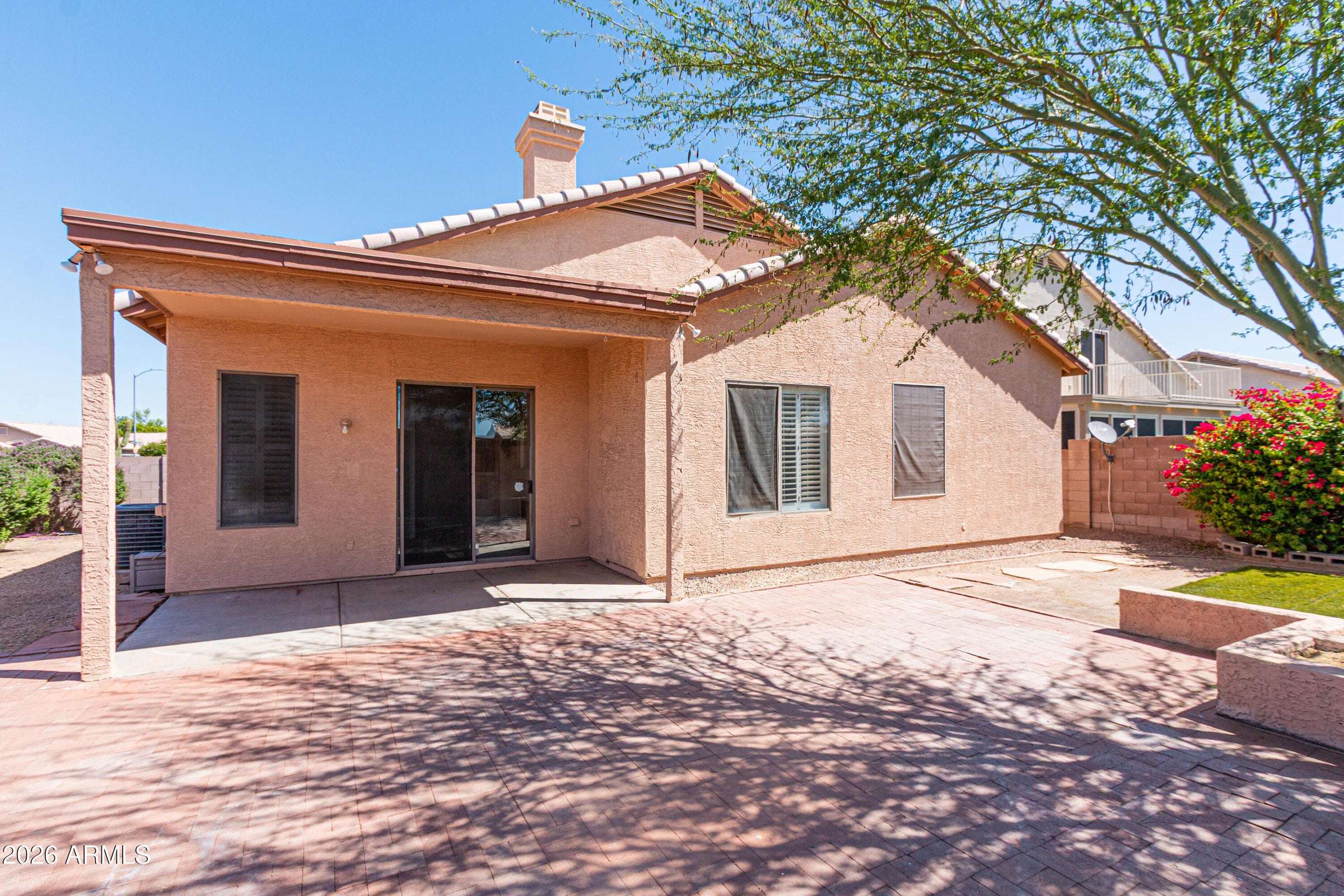 27 of 29. Covered outdoor living area paired with an extended paver patio and landscaped yard. Ideal for gatherings, outdoor dining, and year-round enjoyment in Phoenix.