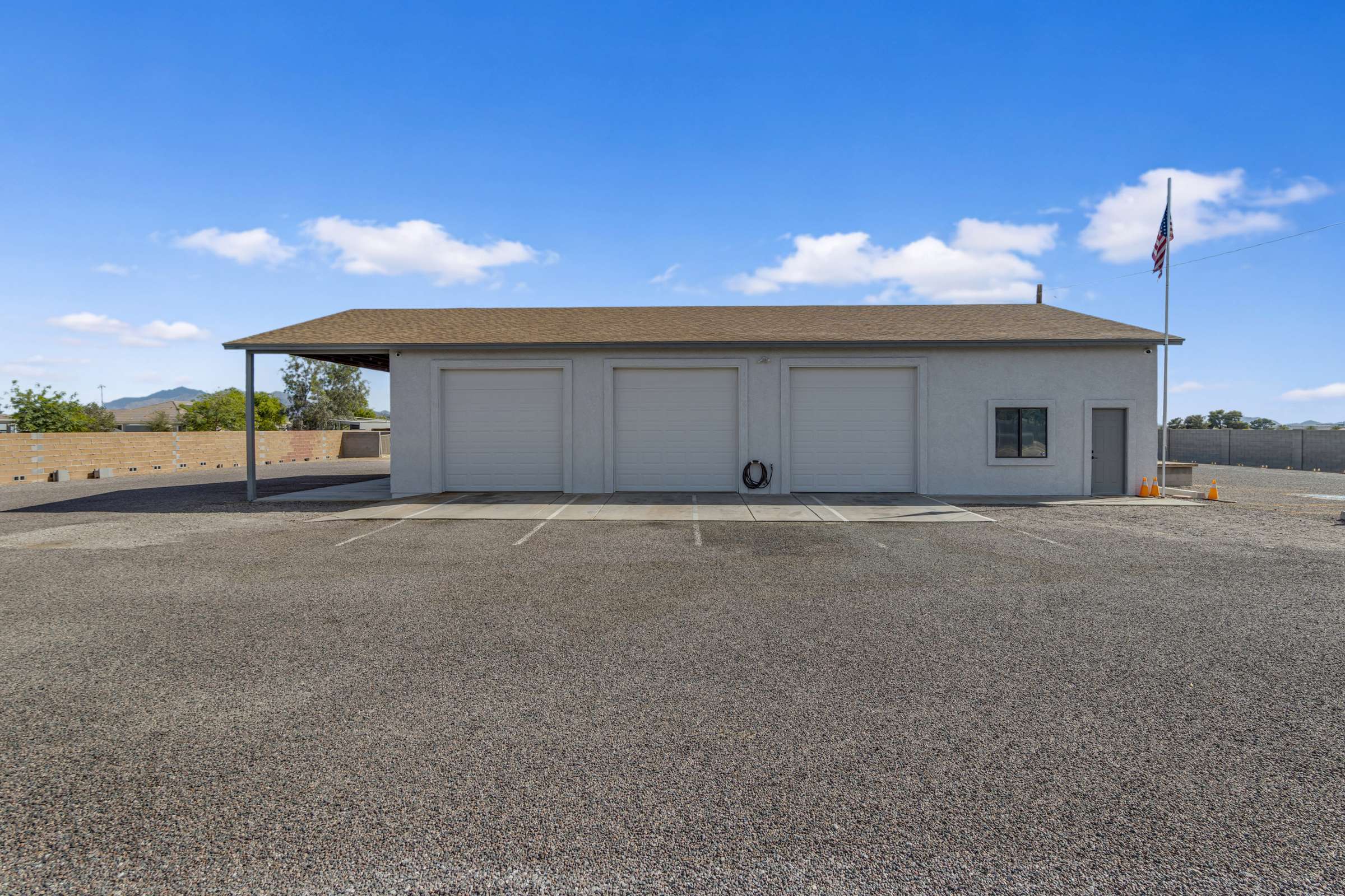 8 of 43. Detached multi-bay workshop with oversized garage doors, covered exterior parking, and expansive work areas designed for vehicle storage, restoration projects, equipment, or business use.