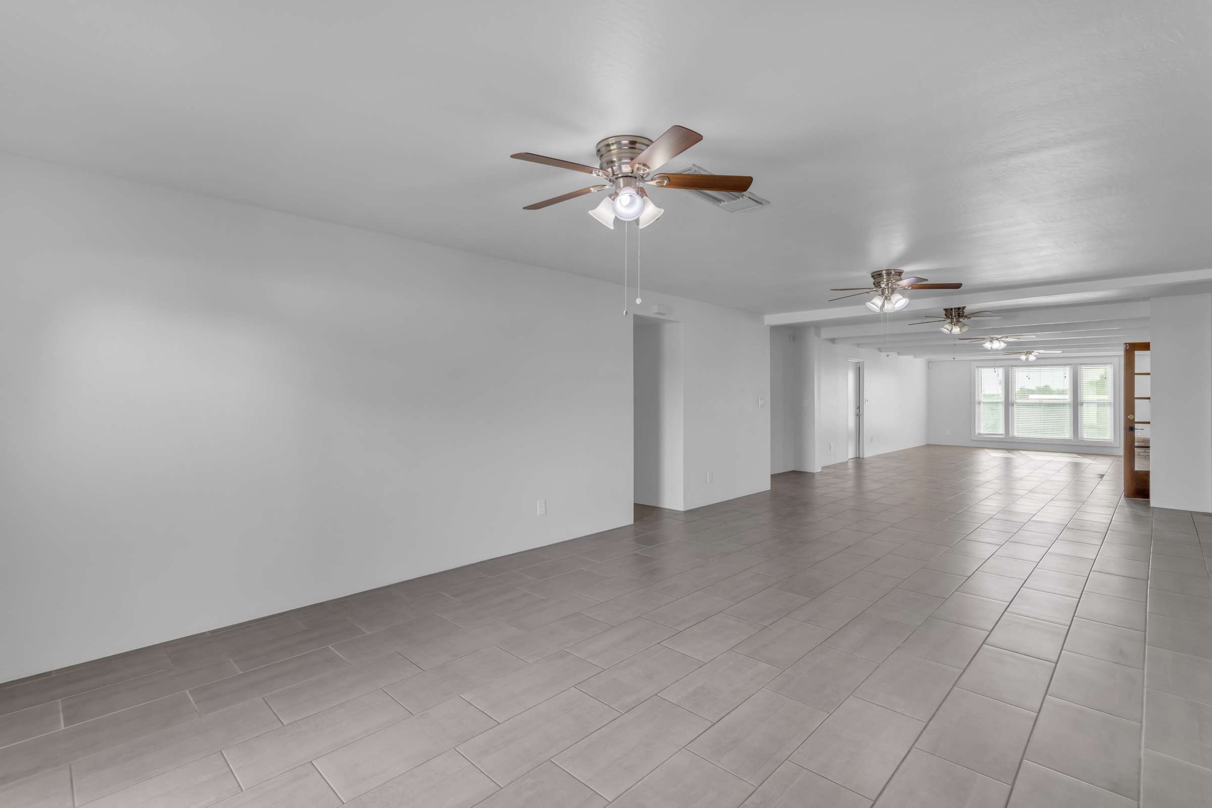18 of 43. Expansive living room showcases the home's impressive scale with durable tile flooring, bright windows, and an open design perfect for entertaining family and friends.