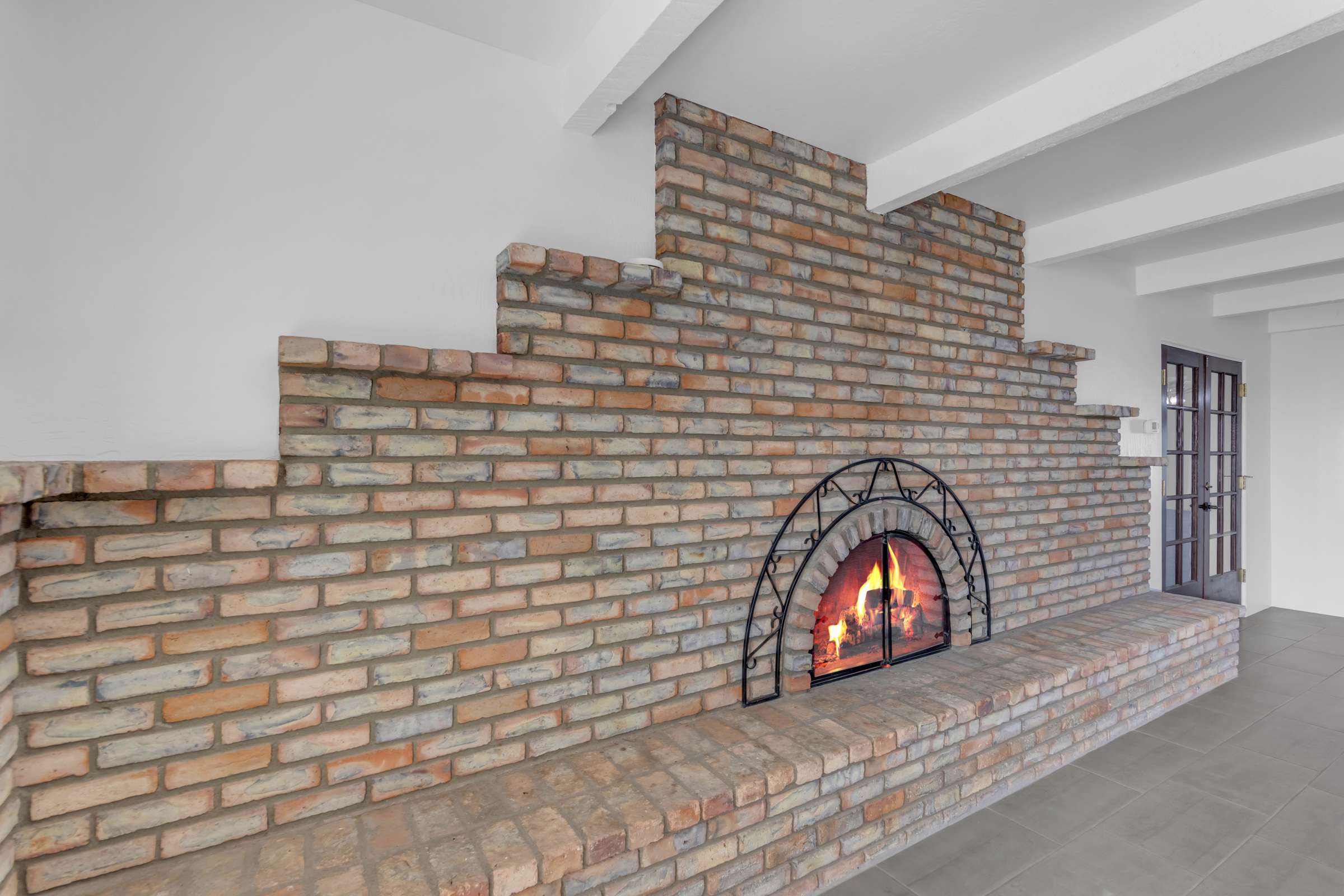 19 of 43. Beautiful full-height brick fireplace adds warmth and character to the home's spacious living area, creating an inviting gathering space with timeless architectural appeal.