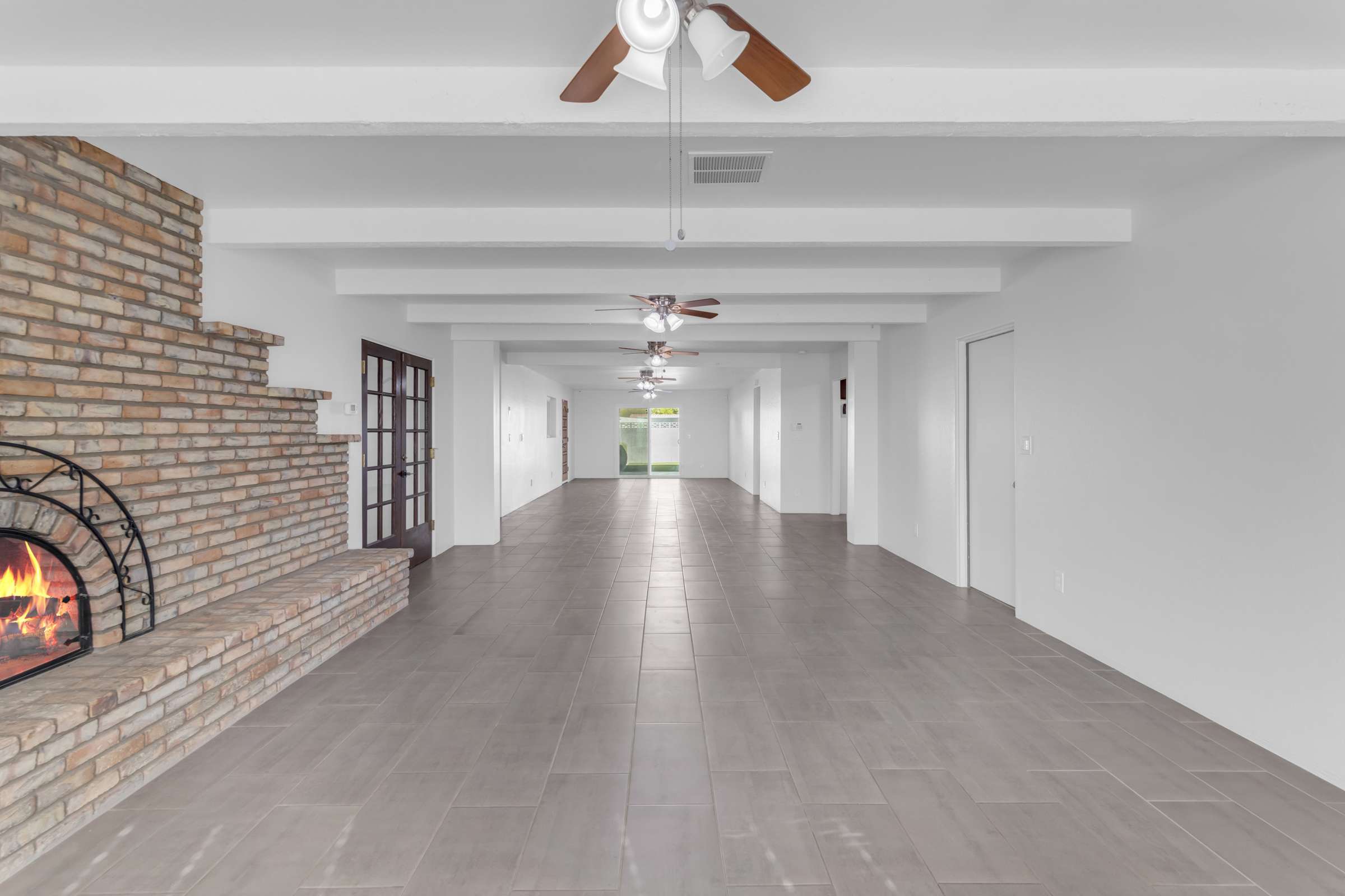 20 of 43. Expansive great room features updated tile flooring, ceiling fans, exposed beams, and a beautiful brick fireplace that anchors the spacious open floor plan, perfect for entertaining and everyday living.
