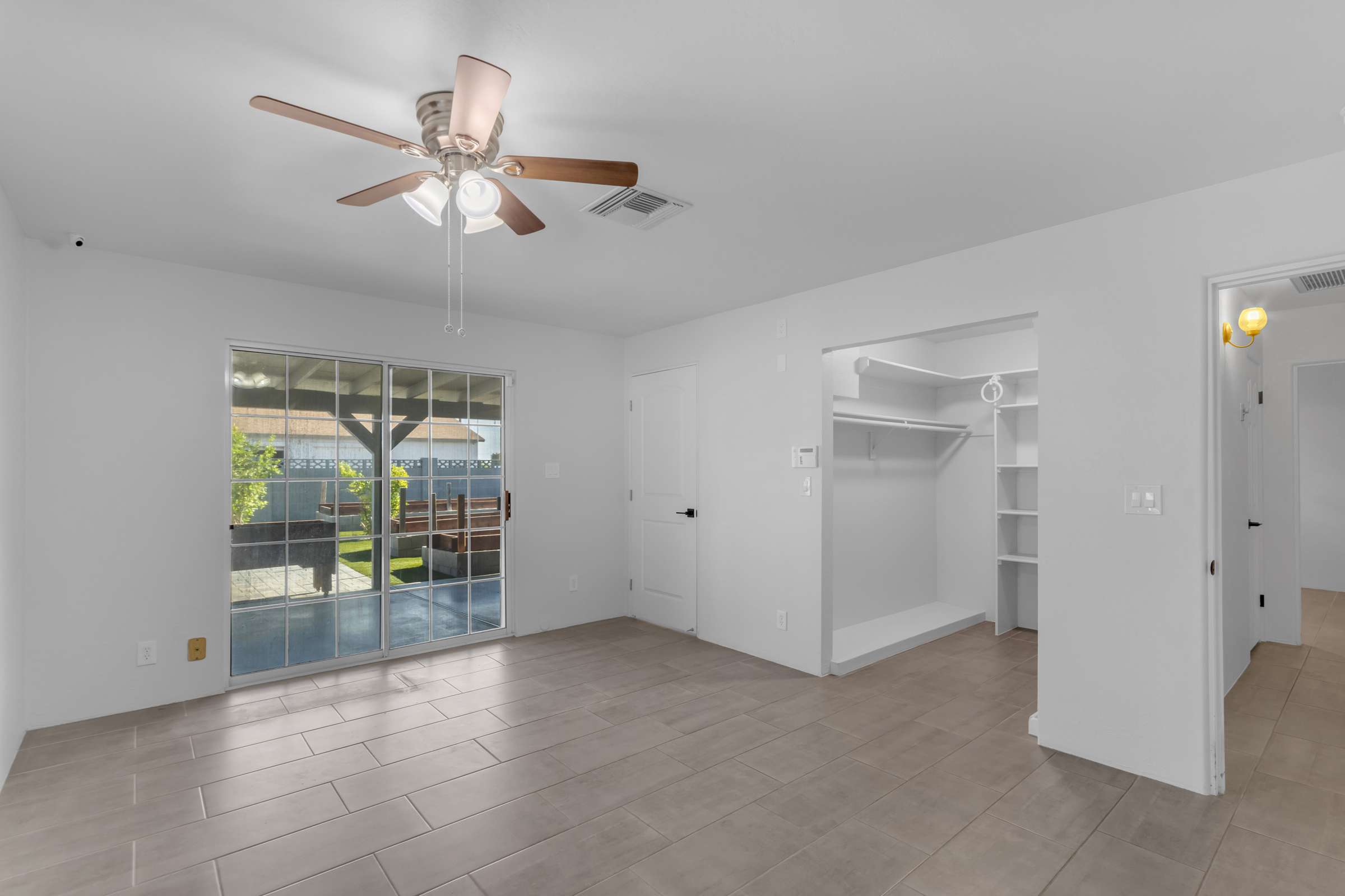 25 of 43. Spacious primary bedroom includes updated flooring, ceiling fan, large sliding glass door, and direct access to the covered patio, blending indoor comfort with outdoor living.
