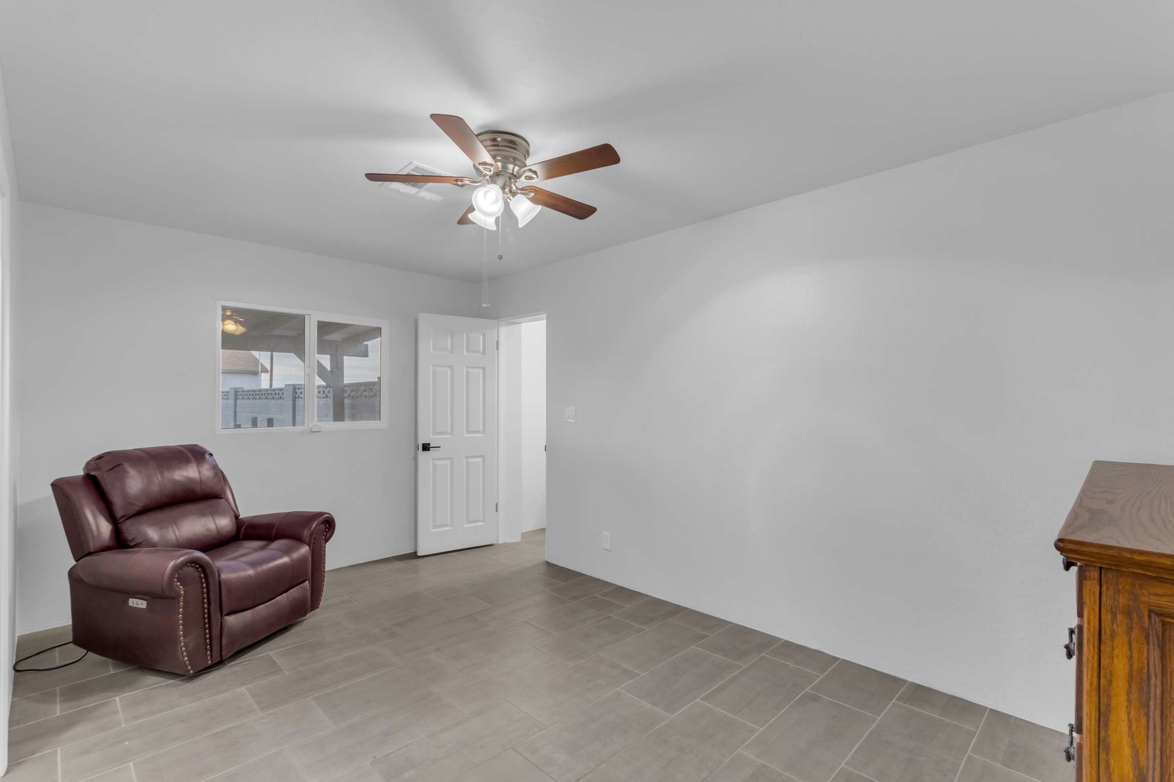 30 of 43. Spacious secondary bedroom offers updated tile flooring, ceiling fan, abundant natural light, and convenient access to the adjoining bathroom, making it ideal for guests or a home office.