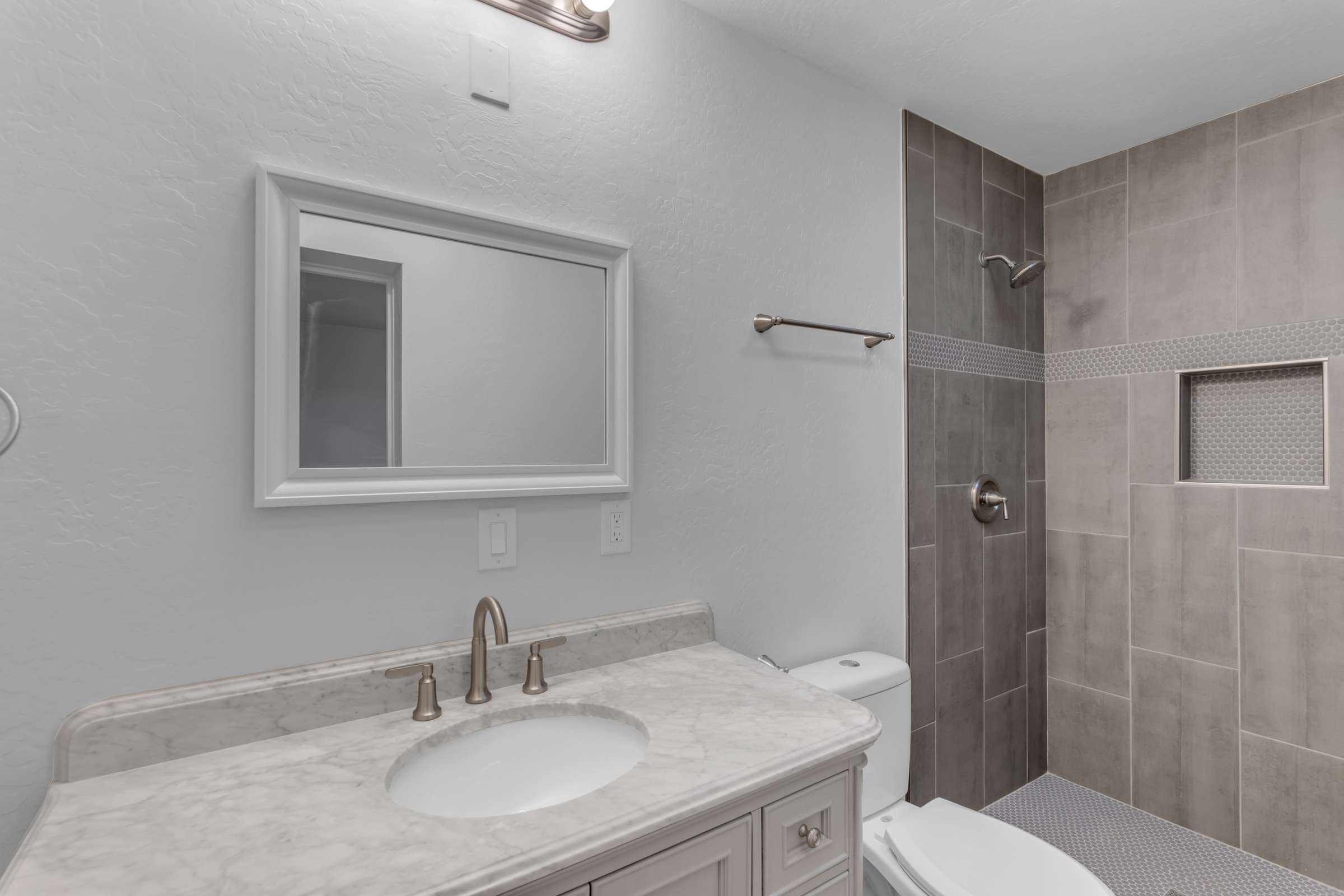 31 of 43. Updated bathroom features a marble-look vanity, contemporary fixtures, and a beautifully tiled walk-in shower, delivering a clean and timeless design with quality finishes.
