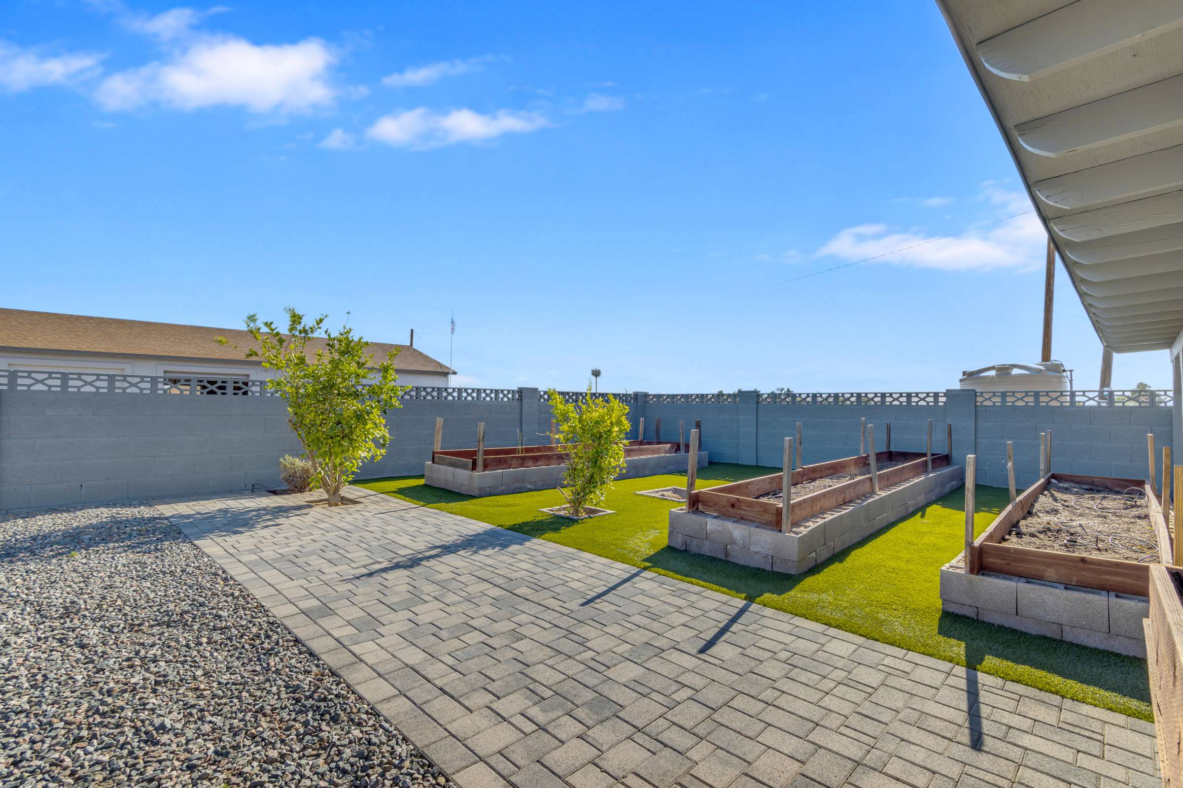 33 of 43. Backyard highlights raised planter boxes, paver walkways, artificial turf, and low-maintenance landscaping, creating an inviting outdoor space for gardening and entertaining.