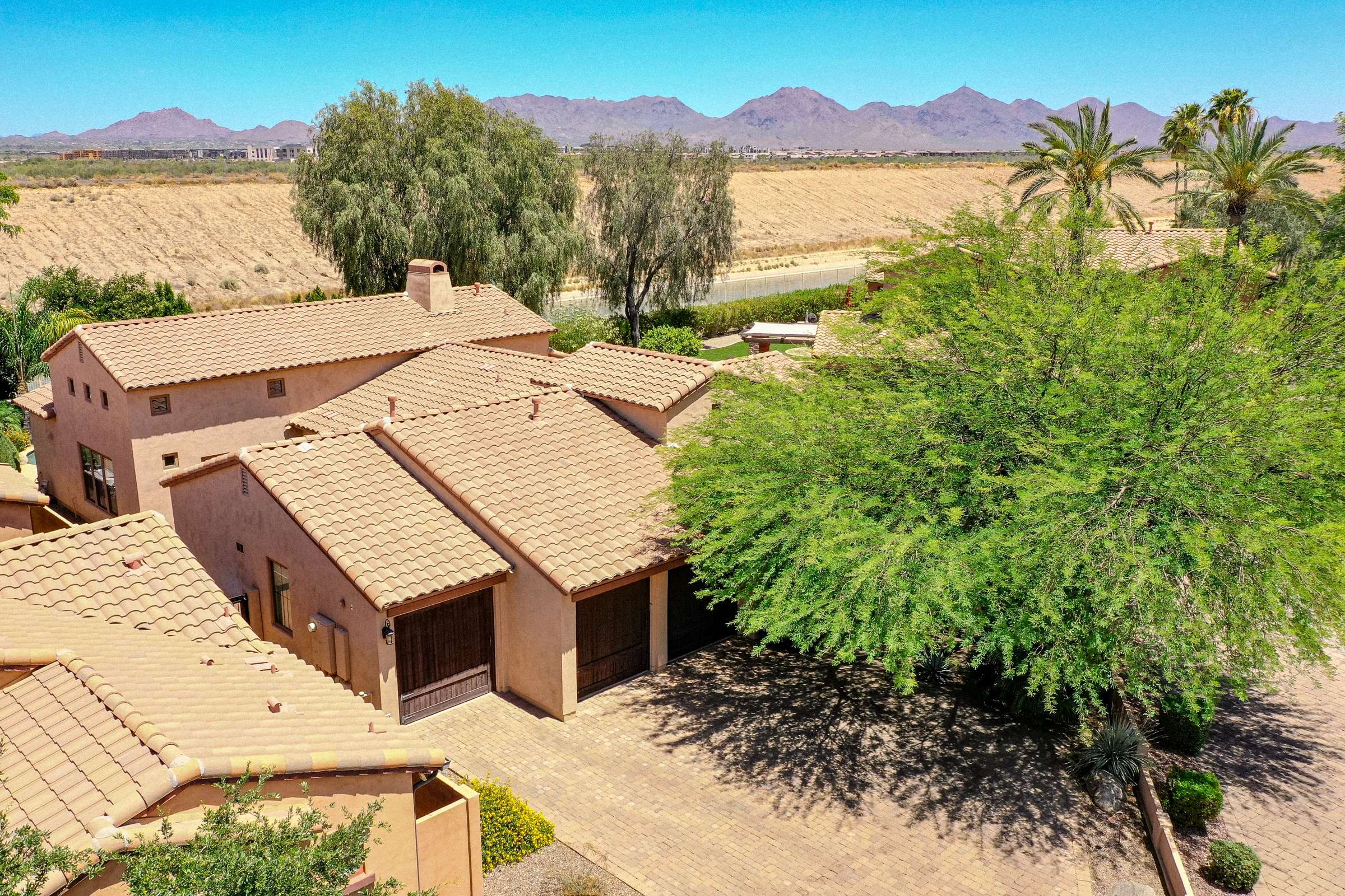 70 of 72. A stunning aerial view captures the home's elegant exterior, oversized paver driveway, mature landscaping, and scenic mountain backdrop. This Scottsdale property offers beautiful curb appeal and an exceptional residential setting.