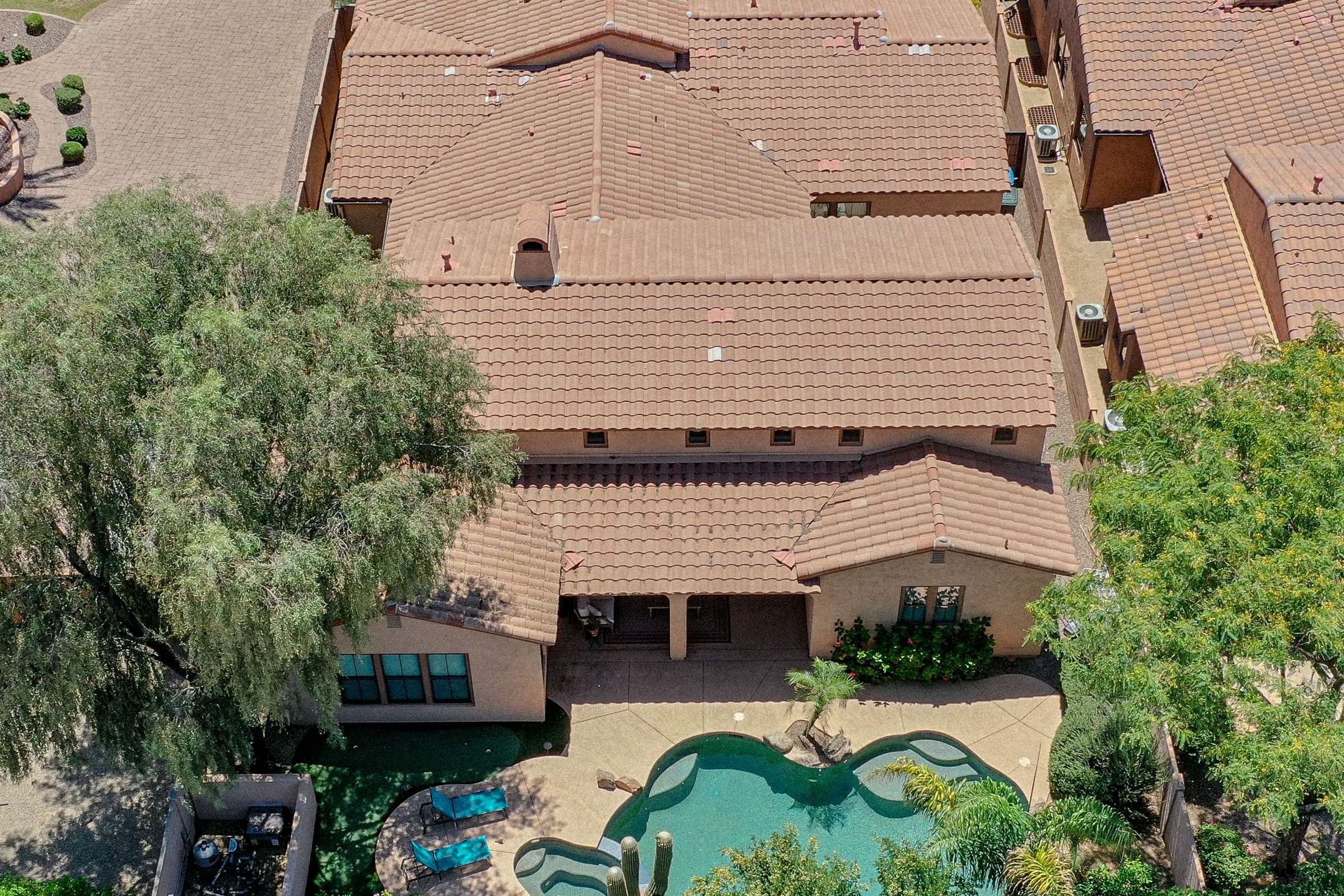 14 of 72. Enjoy a bird's-eye view of the beautifully landscaped backyard featuring a sparkling pool, spa, covered patio, and mature trees. This aerial image highlights the exceptional outdoor living offered by this Scottsdale property.