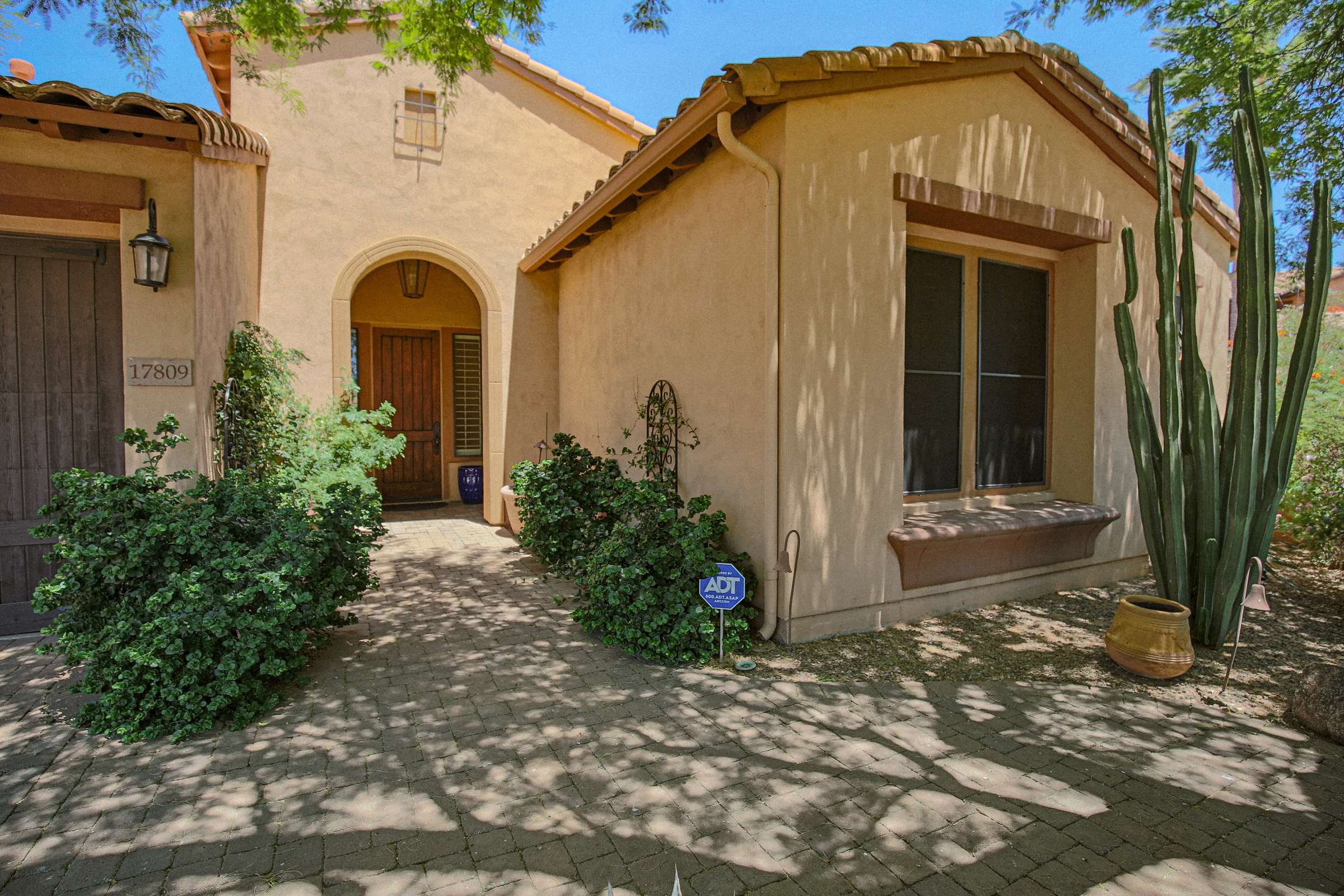 15 of 72. Mature desert landscaping, shaded walkways, and a covered front entrance create a welcoming approach to this beautifully maintained Scottsdale residence within a gated neighborhood.