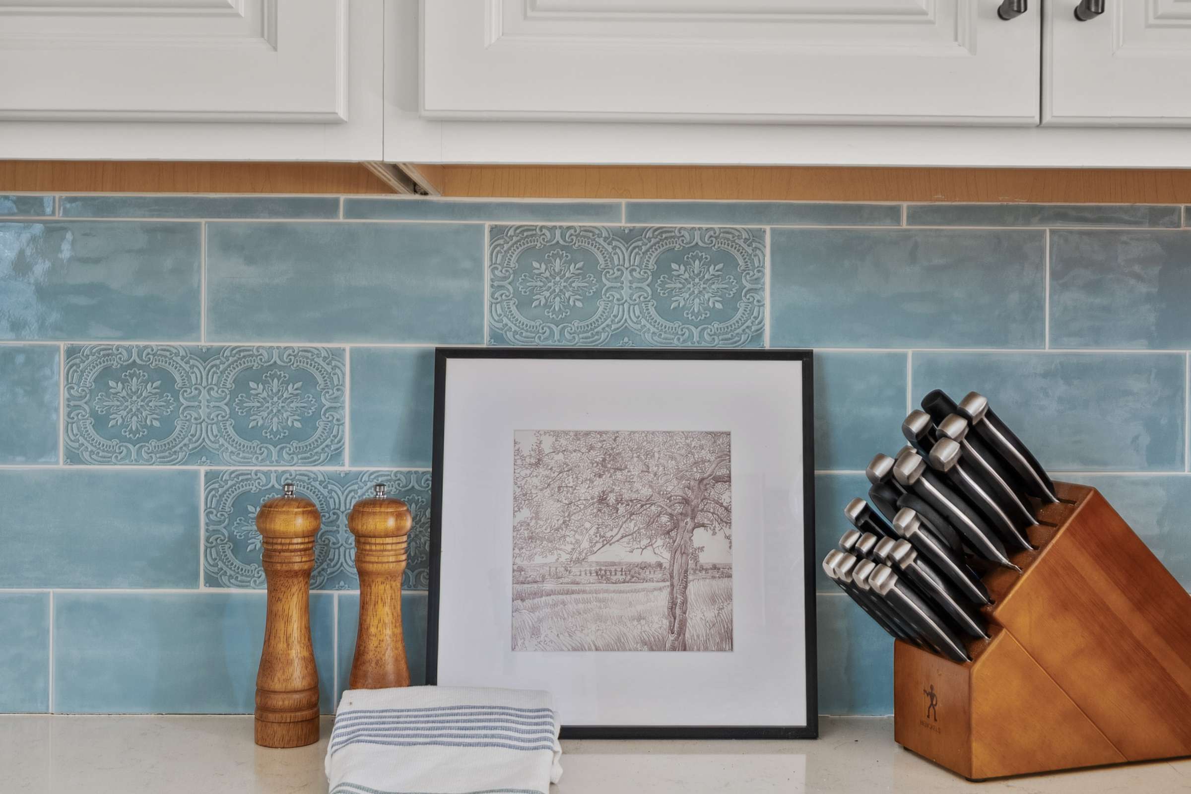 23 of 72. This kitchen workspace showcases expansive quartz countertops, decorative tile accents, custom cabinetry, and ample prep space designed for effortless cooking and entertaining.