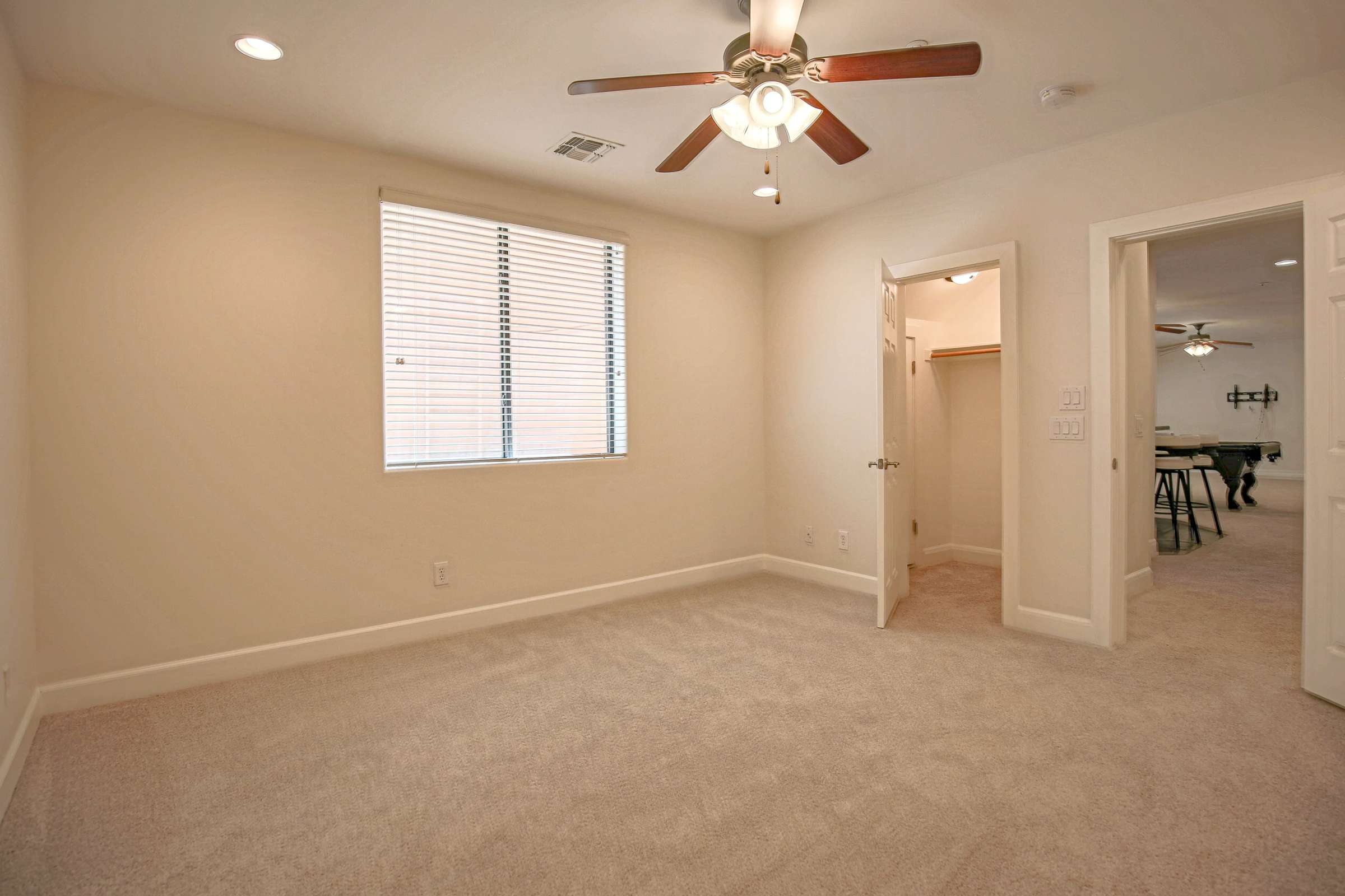 51 of 72. This spacious basement bedroom offers plush carpeting, ceiling fan, recessed lighting, a walk-in closet, and versatile space ideal for guests, hobbies, or a private home office.