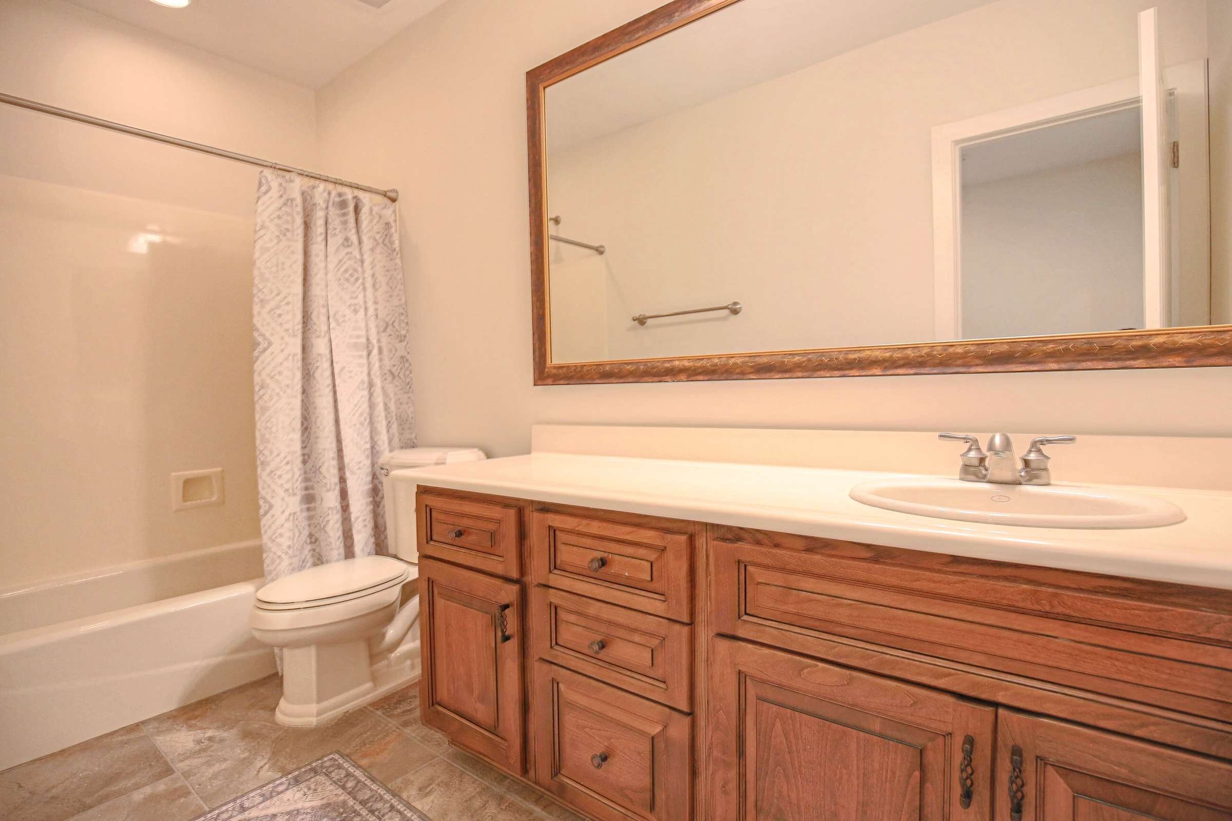 53 of 72. Conveniently located in the finished basement, this full bathroom offers custom wood cabinetry, expansive vanity space, tile flooring, and a tub/shower combination for added functionality.