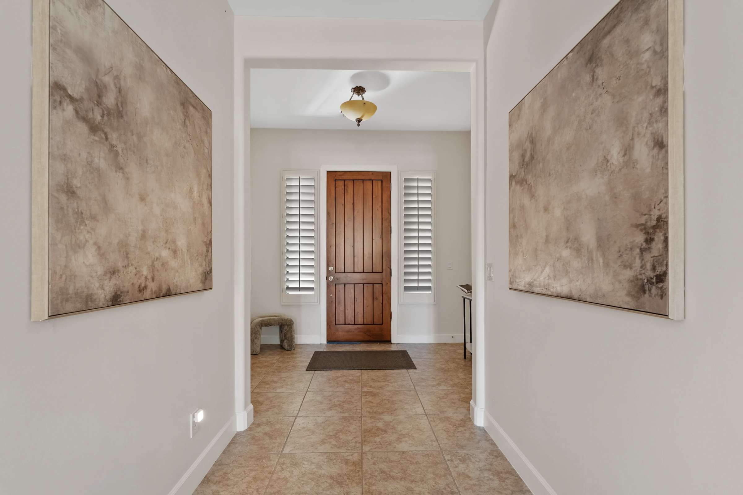 16 of 72. An inviting foyer showcases a custom wood front door, plantation shutters, tile flooring, and clean architectural lines that introduce the home's elegant and spacious interior.