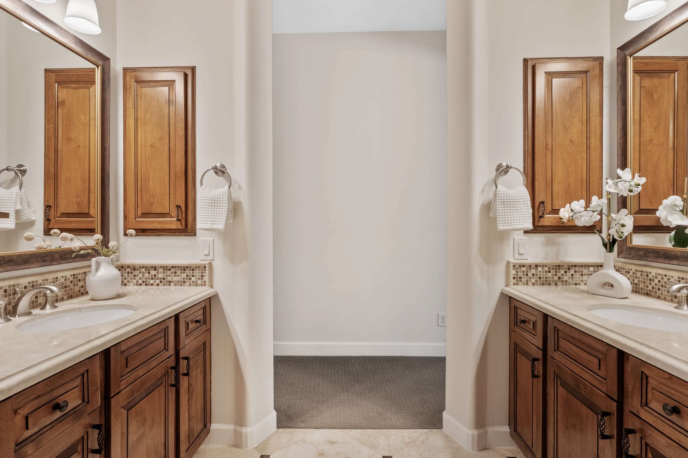 31 of 72. The spacious primary bathroom showcases dual vanities, custom wood cabinetry, stone countertops, decorative tile accents, and elegant finishes that create a luxurious everyday retreat.