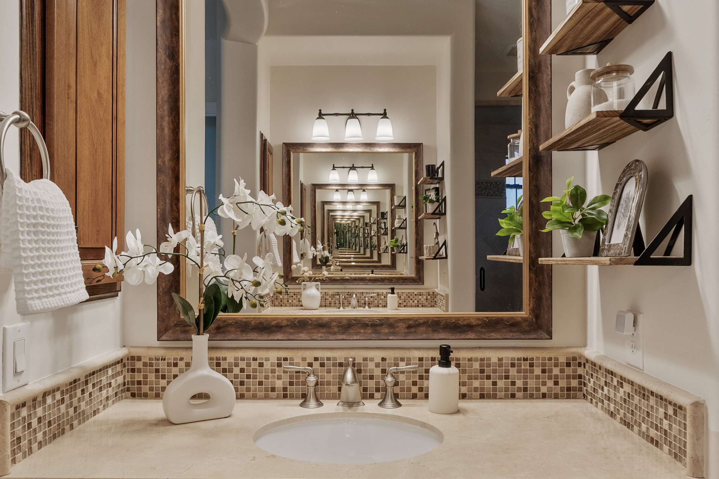 33 of 72. Premium cabinetry, stone countertops, floating shelves, and decorative tile details showcase the craftsmanship and thoughtful design throughout this elegant Scottsdale primary bathroom.