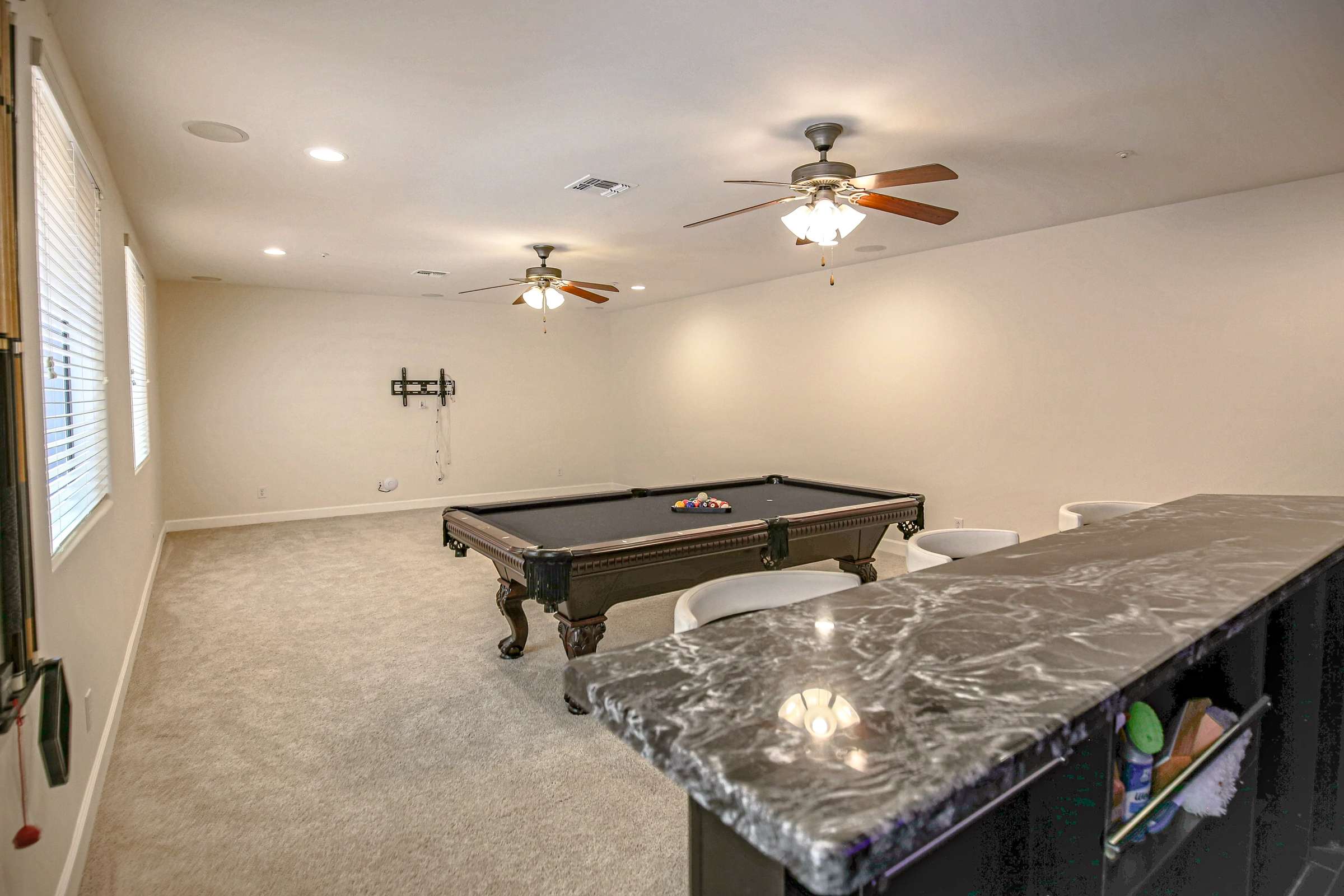 47 of 72. Designed for entertaining, this expansive basement combines open recreation space, a billiards area, recessed lighting, ceiling fans, and a custom wet bar for memorable gatherings.