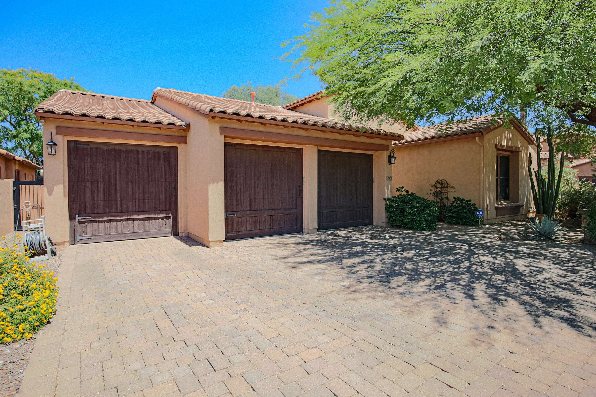 68 of 72. A spacious paver driveway leads to the three-car garage with carriage-style doors, complemented by mature landscaping and attractive architectural details for outstanding curb appeal.