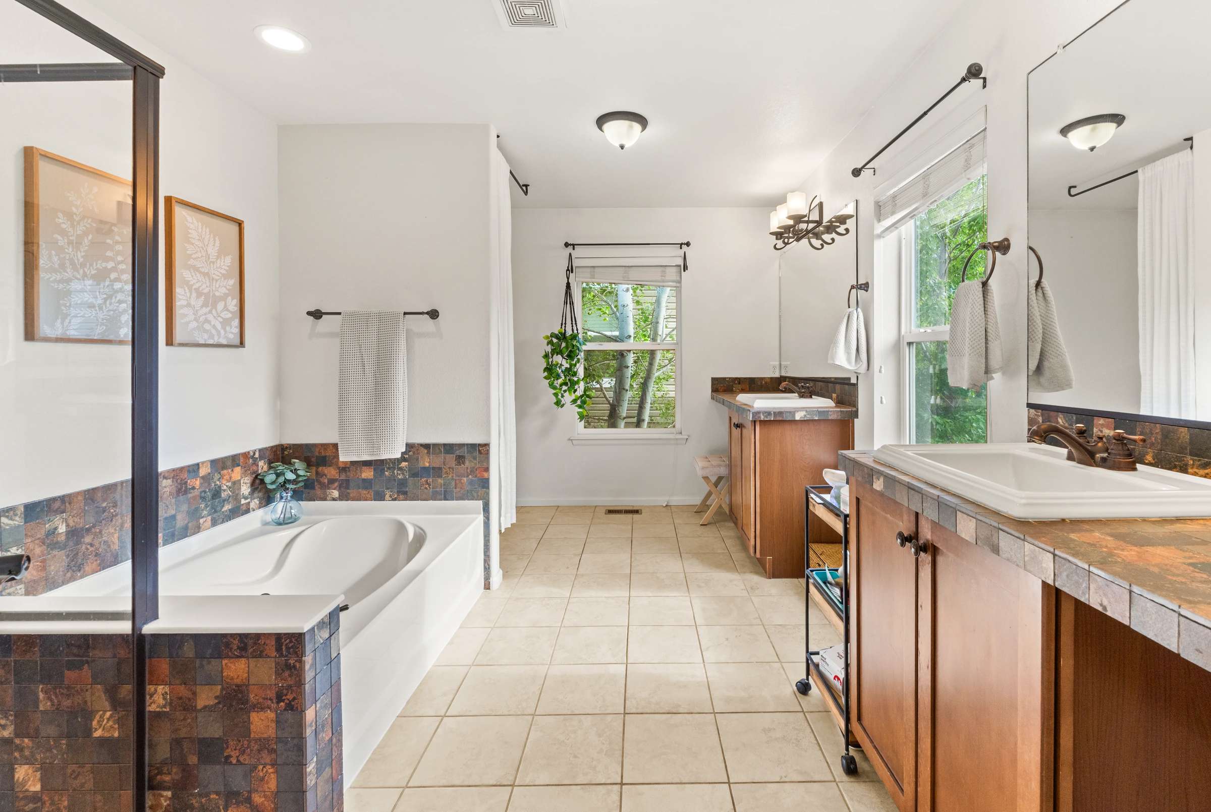 28 of 51. A five-piece primary bathroom is complete with dual vanities, a soaking tub, and separate shower.
