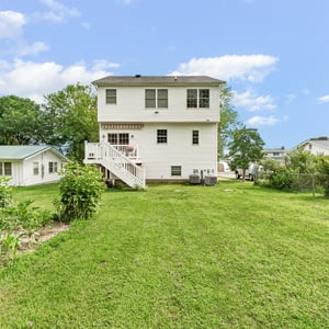 Spacious multi-story home with a large yard, offering potential for outdoor activities and gardening.