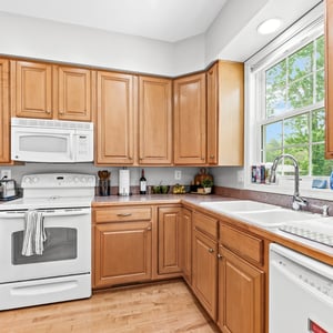Bright and spacious kitchen featuring ample cabinetry, modern appliances, and a sunlit window overlooking the yard.
