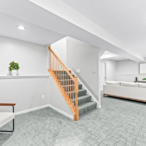 Spacious basement area featuring plush carpeting, natural light, and convenient access to the upstairs living space.