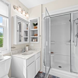 Bright and functional bathroom featuring a modern shower, ample storage, and large windows for natural light.