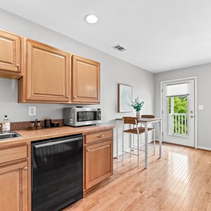 Bright and functional wet bar and living space with modern appliances, seamlessly connected to a welcoming recreation area and outdoor space.