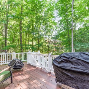 Spacious deck nestled in a lush, wooded setting, perfect for outdoor gatherings and relaxation.