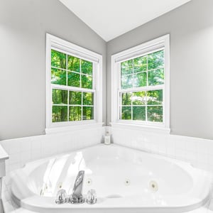 Bright and airy bathroom featuring a spacious jetted tub with windows that invite natural light.