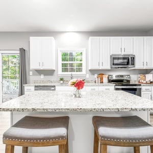 Bright and modern kitchen featuring spacious stone countertops, stainless steel appliances, and a view of the outdoors.