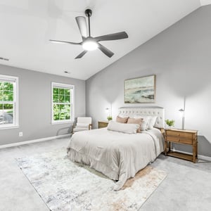 Bright and spacious bedroom featuring vaulted ceilings, large windows, and contemporary furnishings for comfort and relaxation.