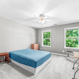 Spacious bedroom featuring large windows, abundant natural light, and ceiling fan for comfortable living.