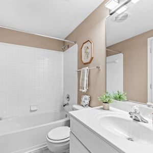 Bright and functional bathroom featuring modern fixtures, a tub-shower combo, and ample storage space.