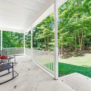 Spacious front porch offers a peaceful retreat, surrounded by mature trees and natural beauty.
