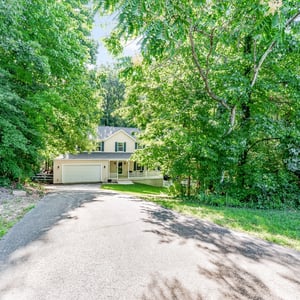 Nestled among lush greenery, this home offers a private driveway and inviting outdoor space for relaxation.