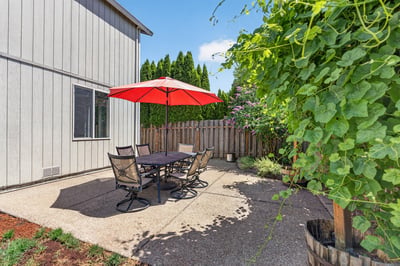 This outdoor space features a shaded patio, perfect for gatherings and enjoying the garden’s greenery.